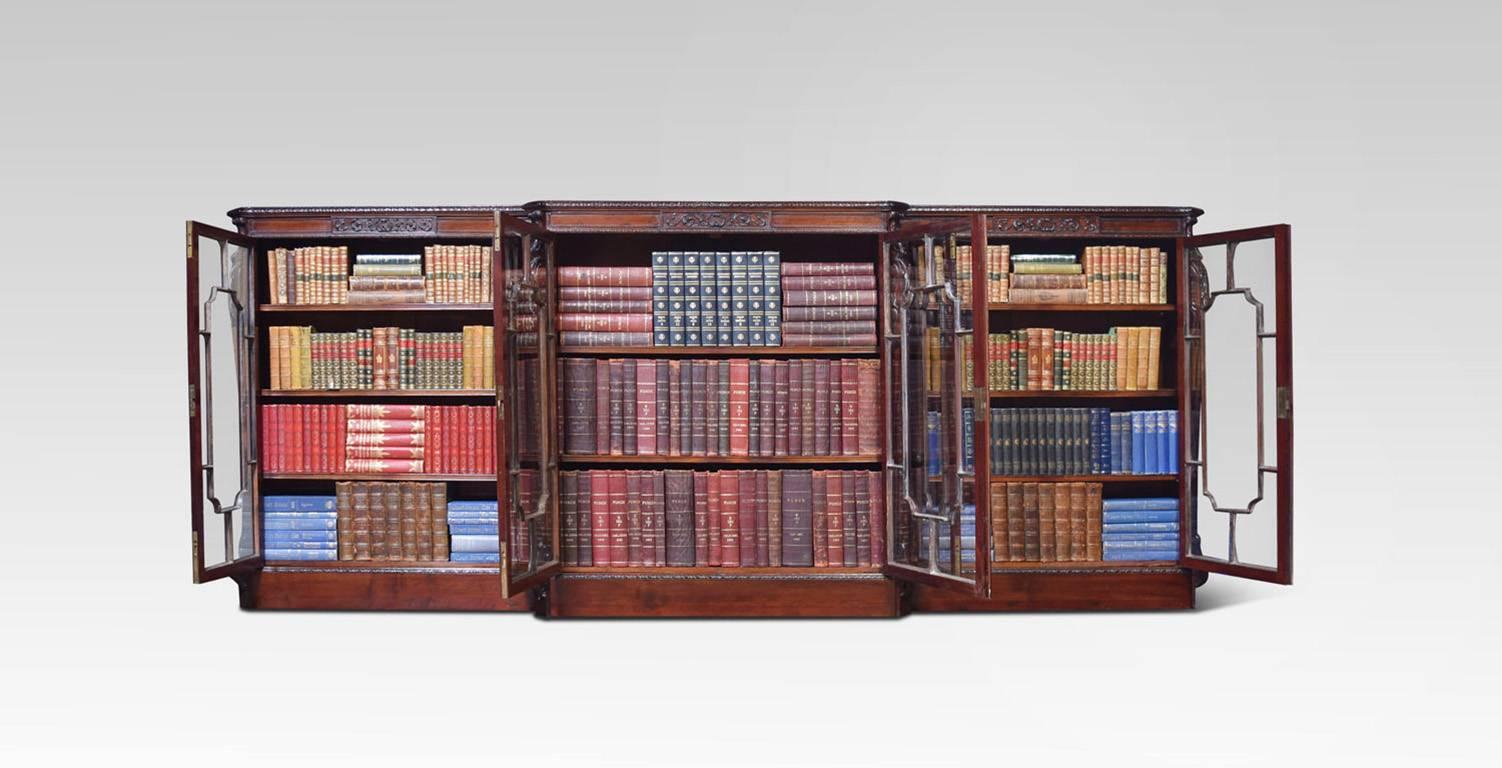 Chippendale revival, mahogany breakfront library bookcase, the large rectangular top with scale moulded edge above six complex lattice glazed doors, fitted with bramah locks. The doors opening to reveal an arrangement of adjustable shelves. flanked