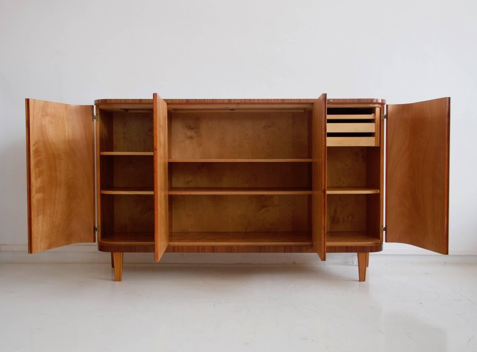 Mahogany cabinet manufactured by AB Seffle Mobelfabrik, 1940s. Front with four doors, the ones on the sides are beautifully curved. Interior shelves and trays. Key available. Restored, no marks.