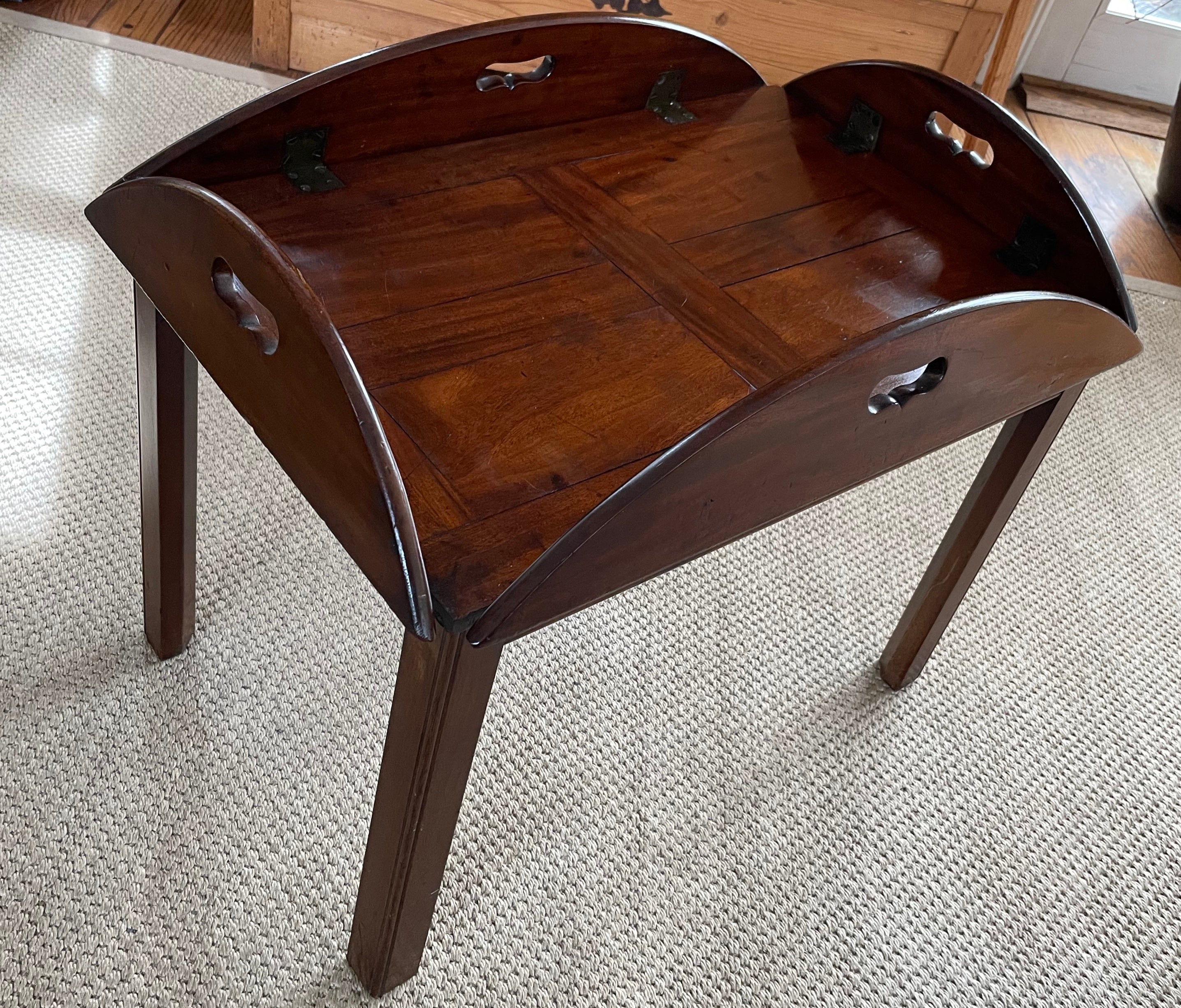 Mahogany butler’s tray table. Vintage butler’s table/ yacht coffee table with paneled surface and soft patinaed brass hardware to raise and lower carved open work sides affixed to tray stand legs. United States, circa 1940’s
Dimensions: 18 1/4” H x