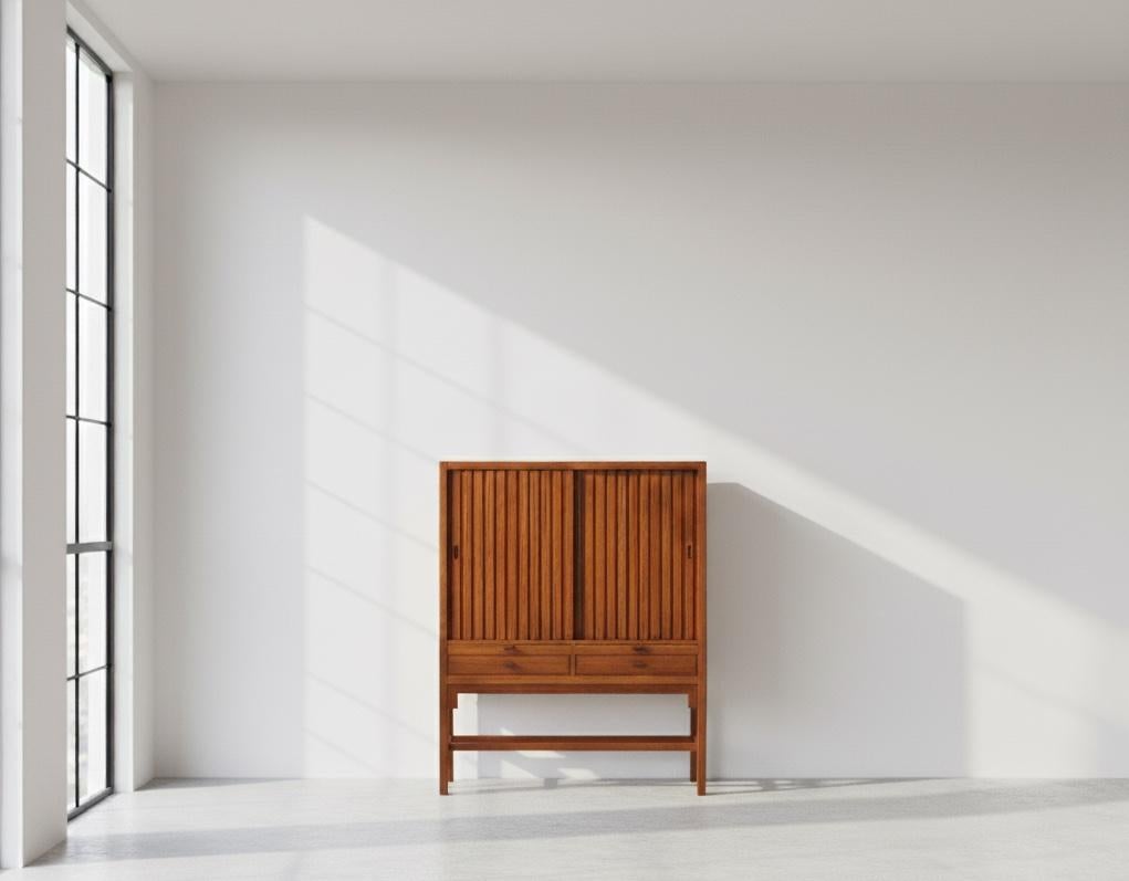 Elegant cabinet designed by Hans J. Wegner in the 1950s, crafted in mahogany. The piece features two sliding doors, pull-out shelves, and drawers, offering versatile storage and functionality—ideal as a bar cabinet or for general storage.

A rare