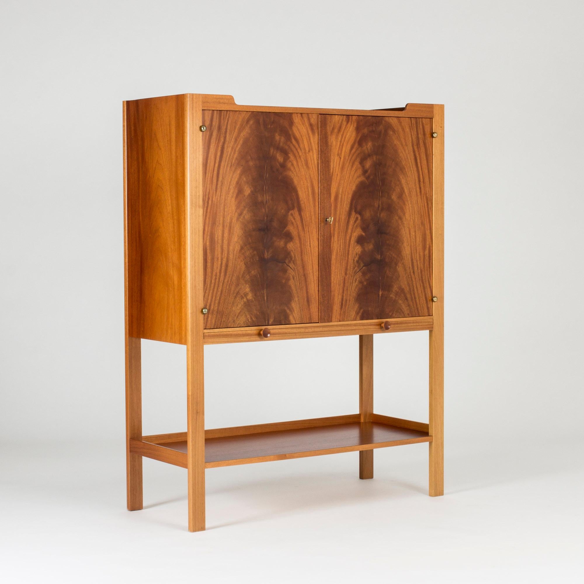 Striking mahogany cabinet by Josef Frank. Boxy yet light design with a dramatic veneer pattern on the doors. Shelves can be pulled out at the bottom of the cabinet.