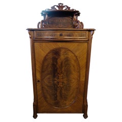 Mahogany cabinet decorated with wood carvings and intarsia from around the 1880s
