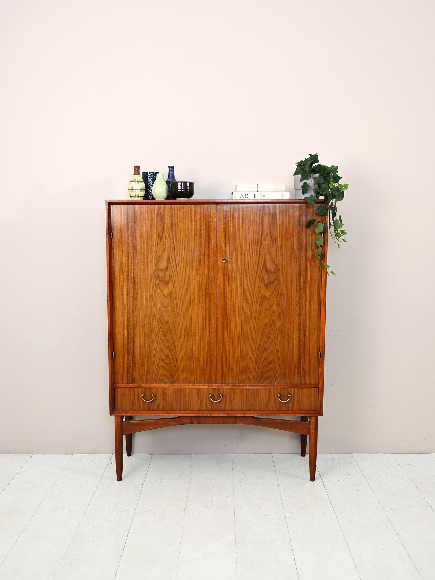 1950s cabinet with shelves and drawers.
 
An original vintage furniture piece with a retro flavor. The gilded doors and handles on the drawers echo the vintage taste and style.
The slender legs slender the frame and give it a modern look.
Ideal
