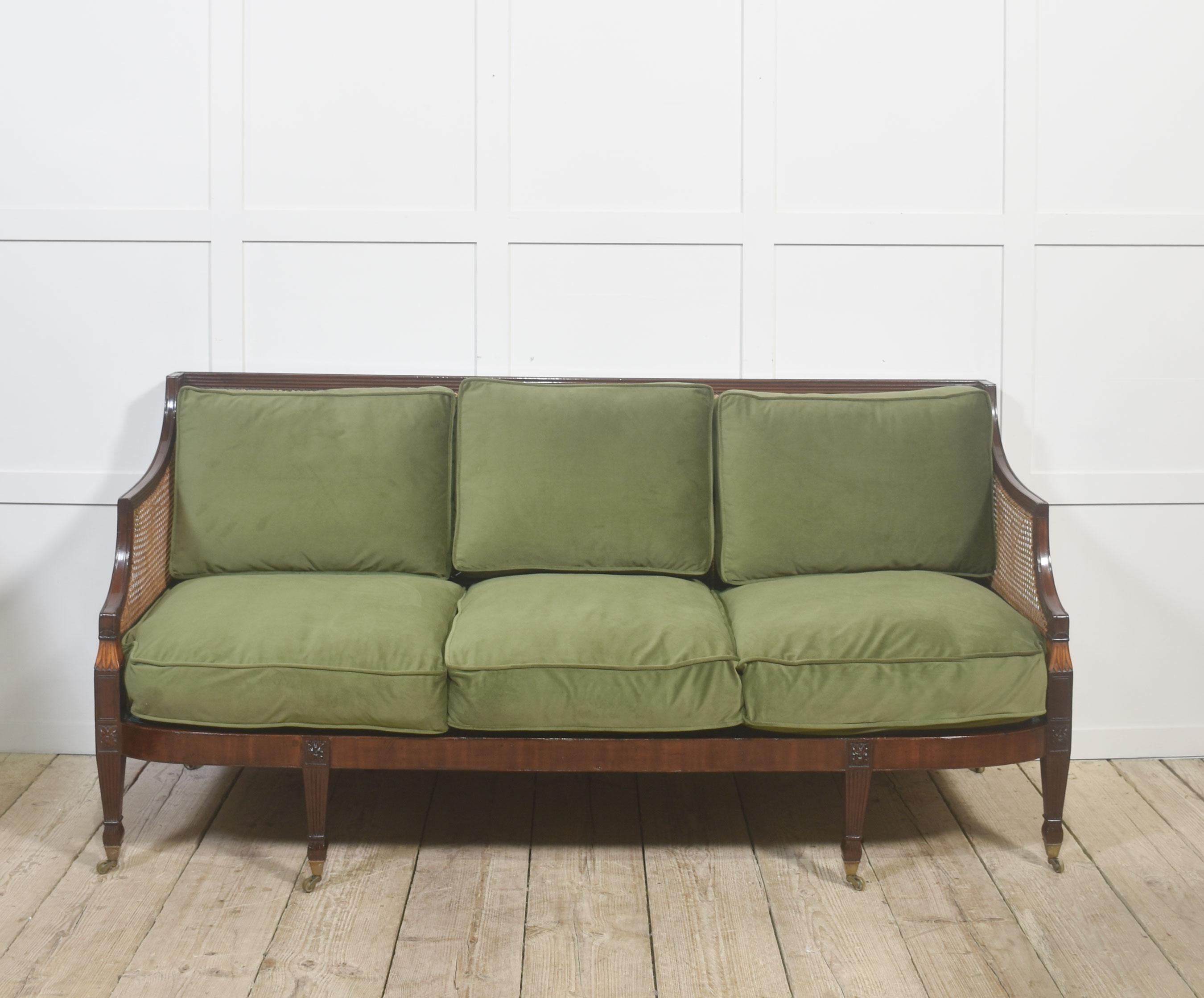 Cet élégant canapé est doté d'un cadre en acajou massif magnifiquement travaillé, enrichi d'une finition chaude et polie qui met en valeur ses lignes classiques. Des panneaux de cannage tissés à la main traversent le dos et les côtés, créant une
