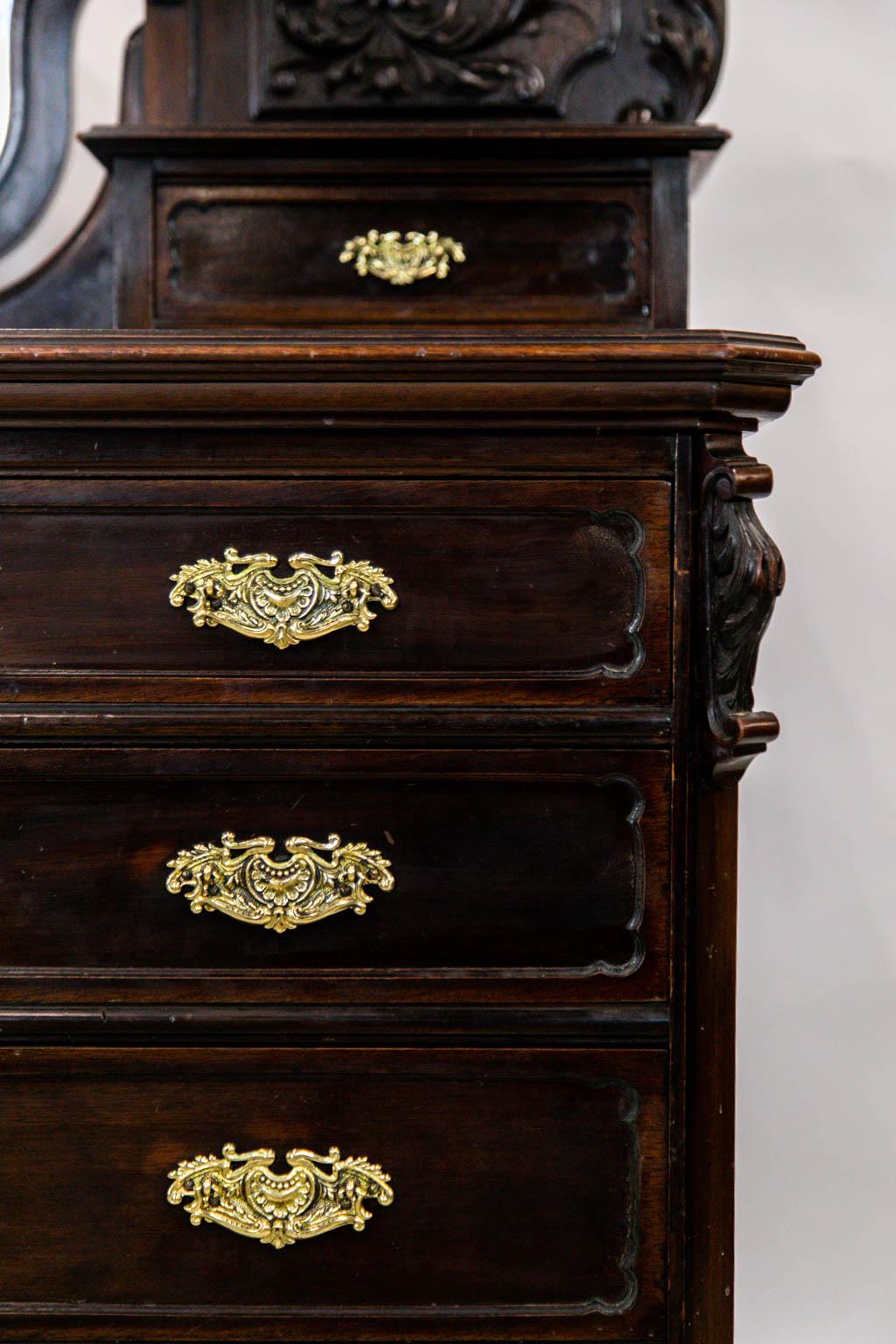 This carved dressing chest is solid mahogany, including the drawer liners. The top has a shaped double mirror framed with carved floral cartouches and an open fretwork broken arch. All hardware is original and has been polished and lacquered for
