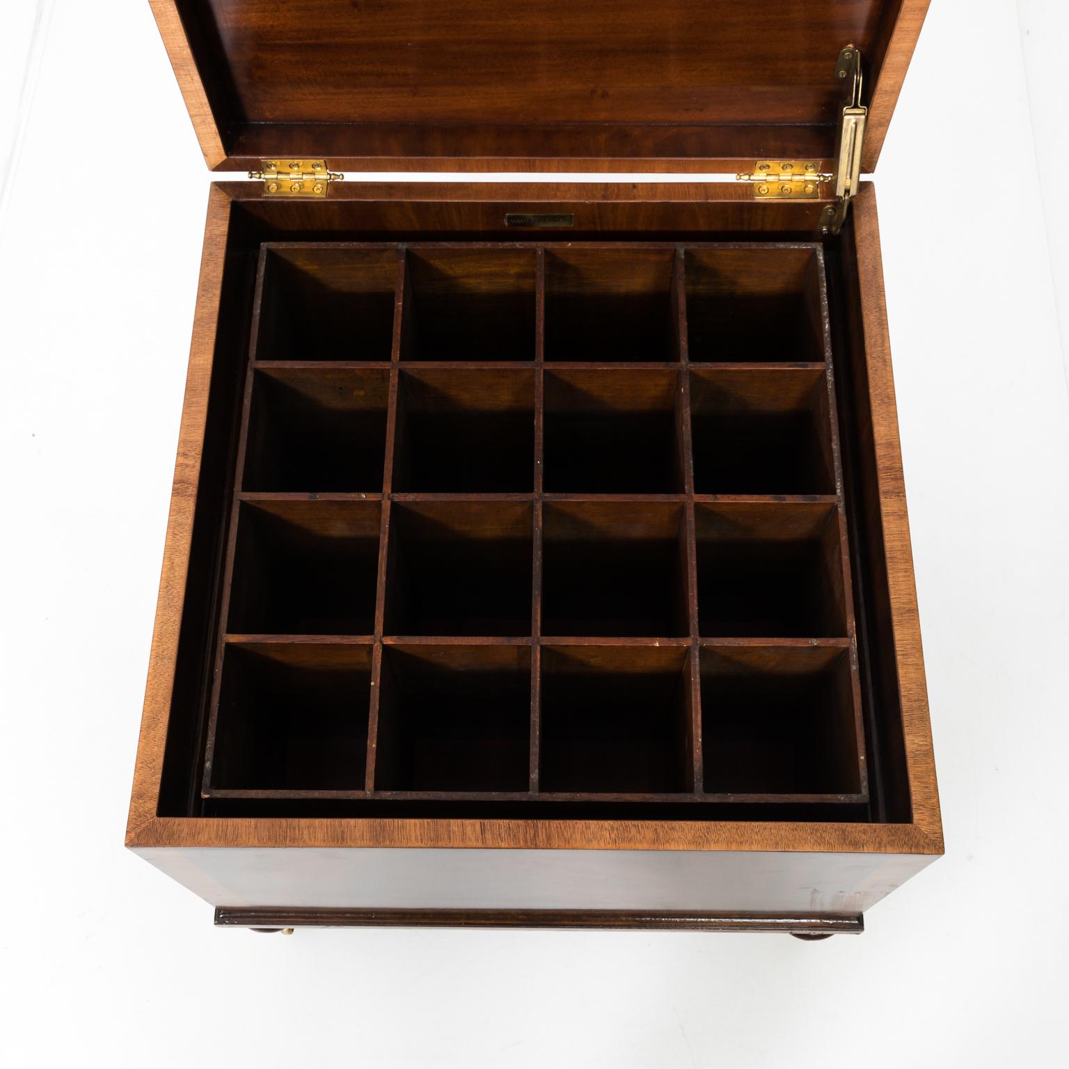 Circa 20th century square cellaret in mahogany by Maitland-Smith with sixteen compartments. The piece also features brass hardware decorated with foliage and castors. A maker's plaque is also found on the inside. Please note of wear consistent with