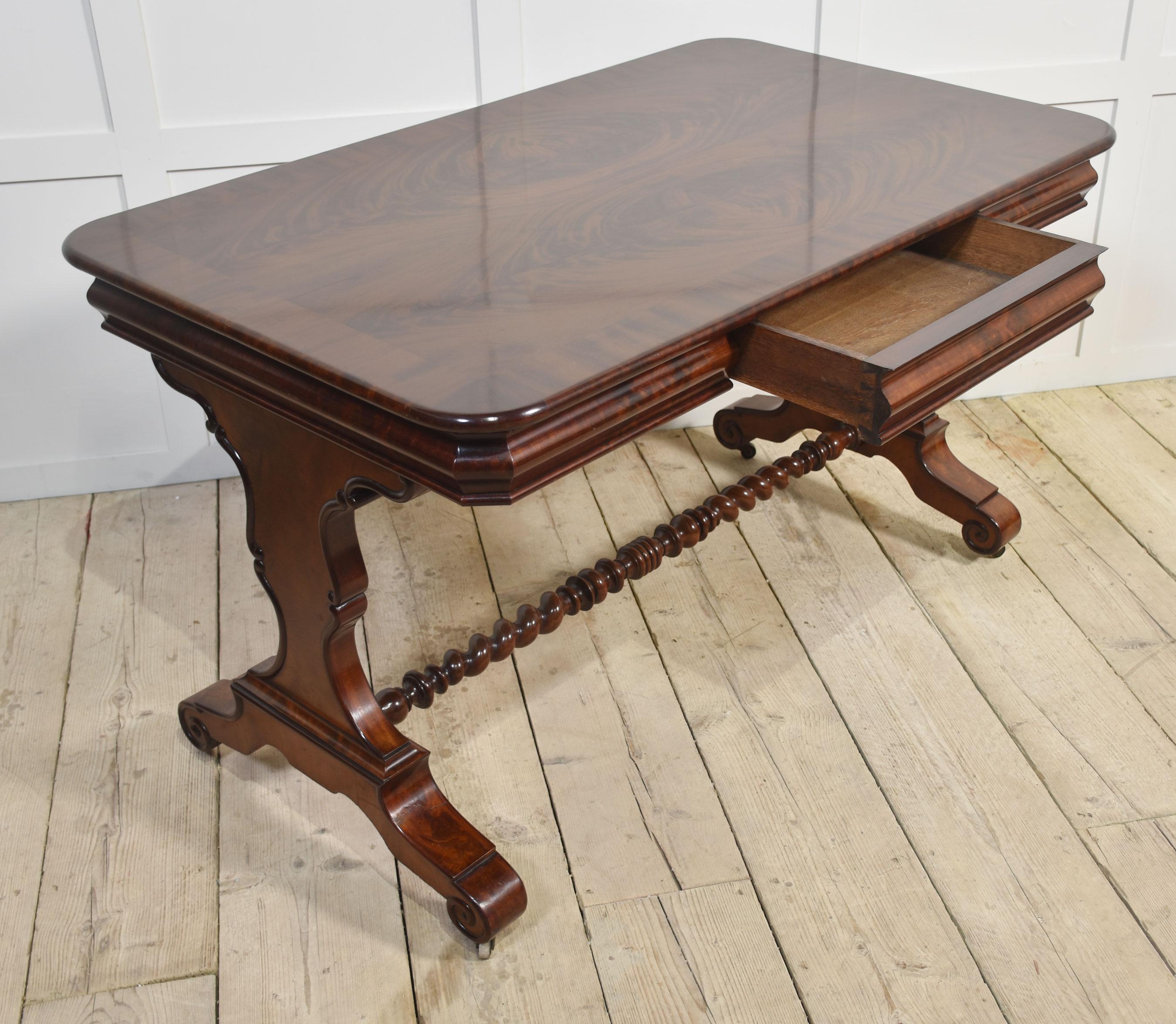 Mahogany writing table, the large rectangular figured mahogany crossbanded top above freeze drawer. All raised up on platform end supports terminating in scrolling feet and casters united by a barley twist stretcher.
Dimensions
Height 30.5