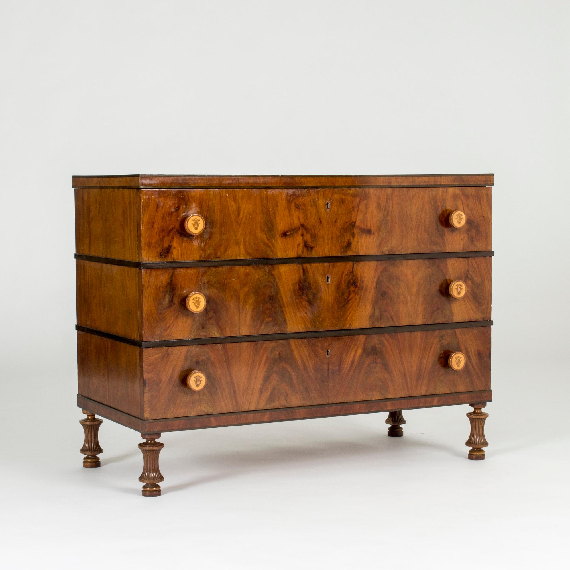 Stunning chest of drawers by Otto Schulz, made with lively mahogany veneer and beautifully sculpted legs. Large, round handles in a contrasting light wood with inlays of a stylized bouquet.

Otto Schulz was a furniture designer, interior designer,