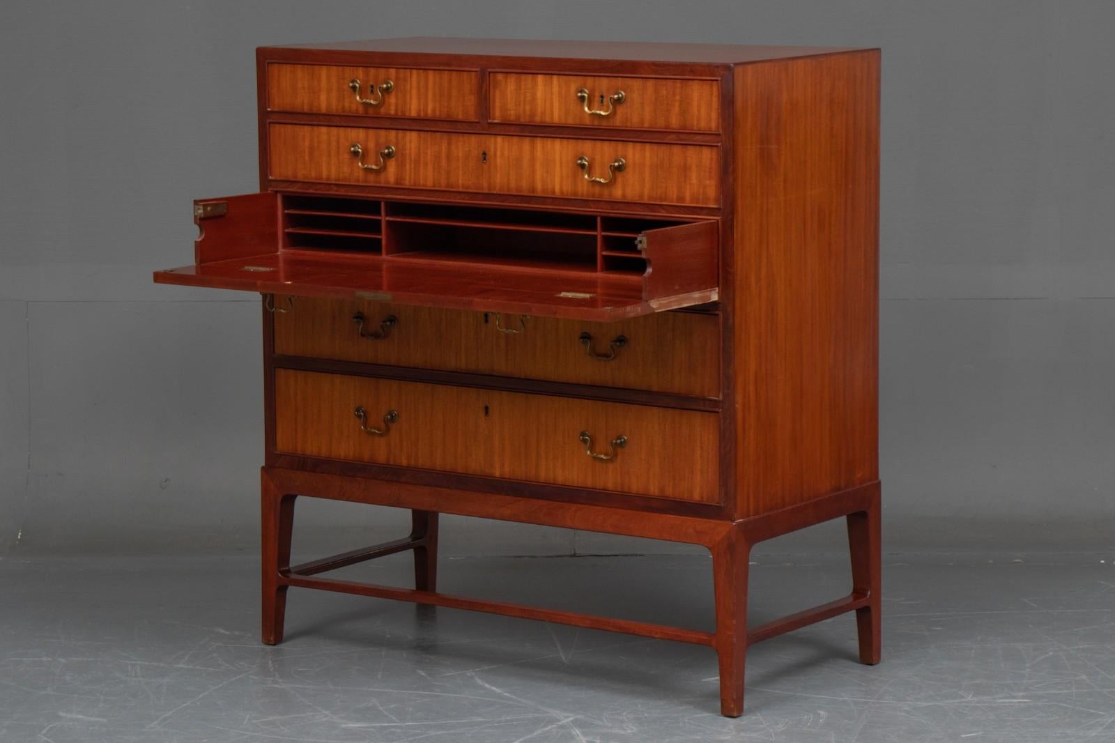 Golden Mahogany Danish modern chest of drawers / secretary by master-carpenter of veneered and solid mahogany, front with six drawers and handles of brass, middle drawer with pull-out and flap behind which smaller compartment. No key. Elegant