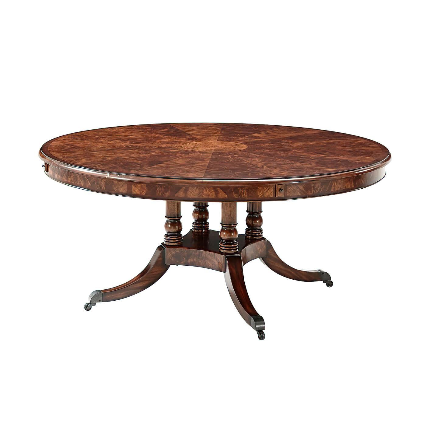 A mahogany and okum veneer circular extending dining table, the top with a molded edge and pull out lopers supporting four crescent-shaped crossbanded extension leaves, on four turned supports with concave sided platform base issuing downswept legs