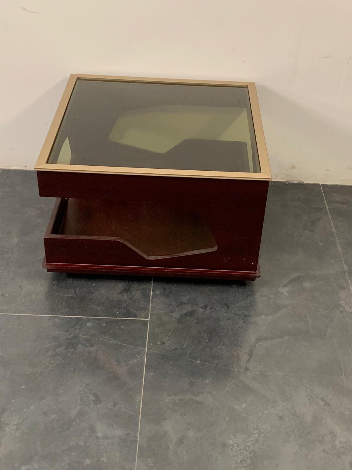 Singular coffee table from the 70s with futuristic lines, beautiful combination of mahogany and the profile of the top and the glass both burnished, under the base of the wheels.
Packaging with bubble wrap and cardboard boxes is included. If the