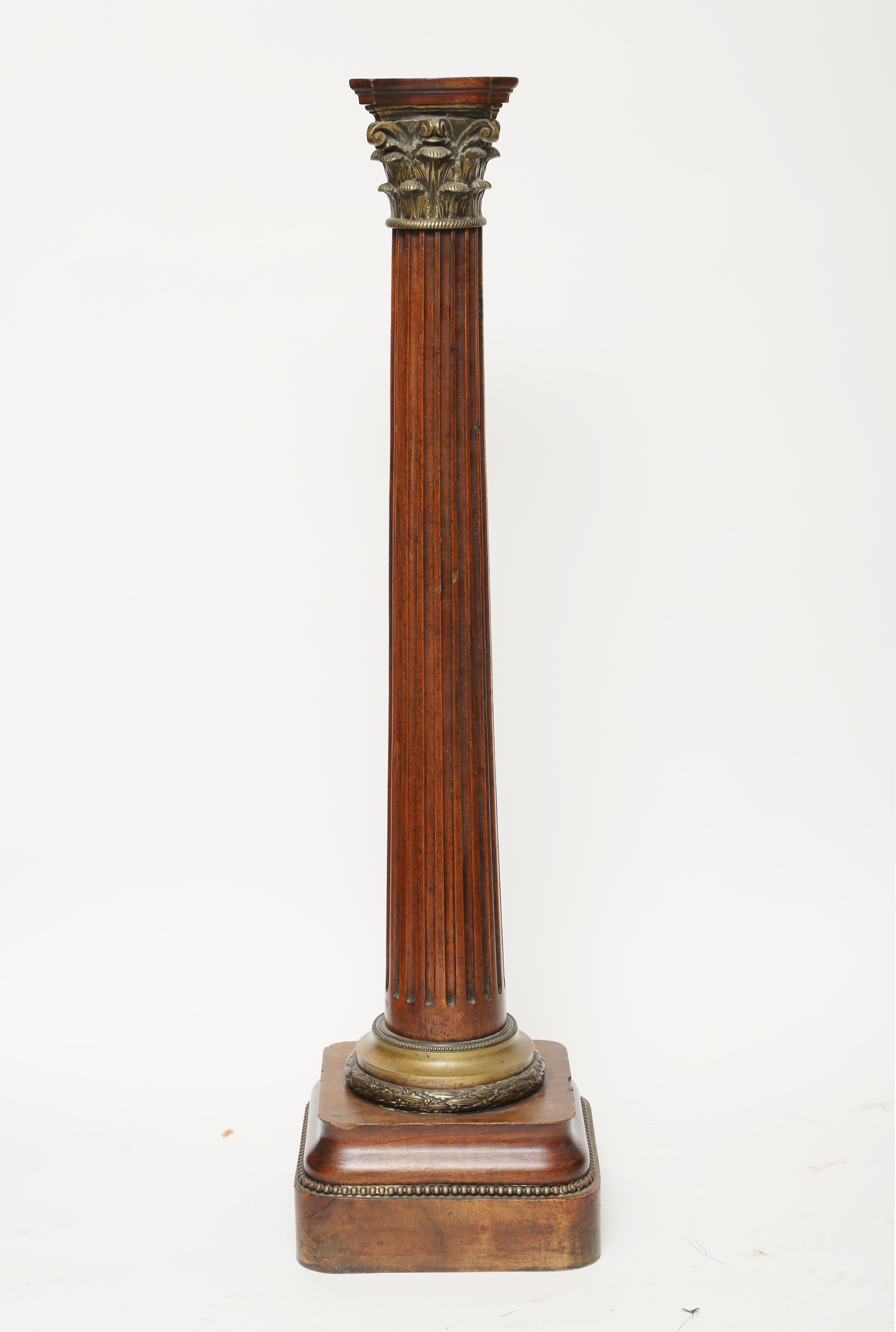 A mahogany fluted column with a gilt brass Corinthian capital. The column terminates with a brass collar of laurel leaves and beaded trim. The round cornered base also has a beaded trim.
I see this piece used as a table column a la 