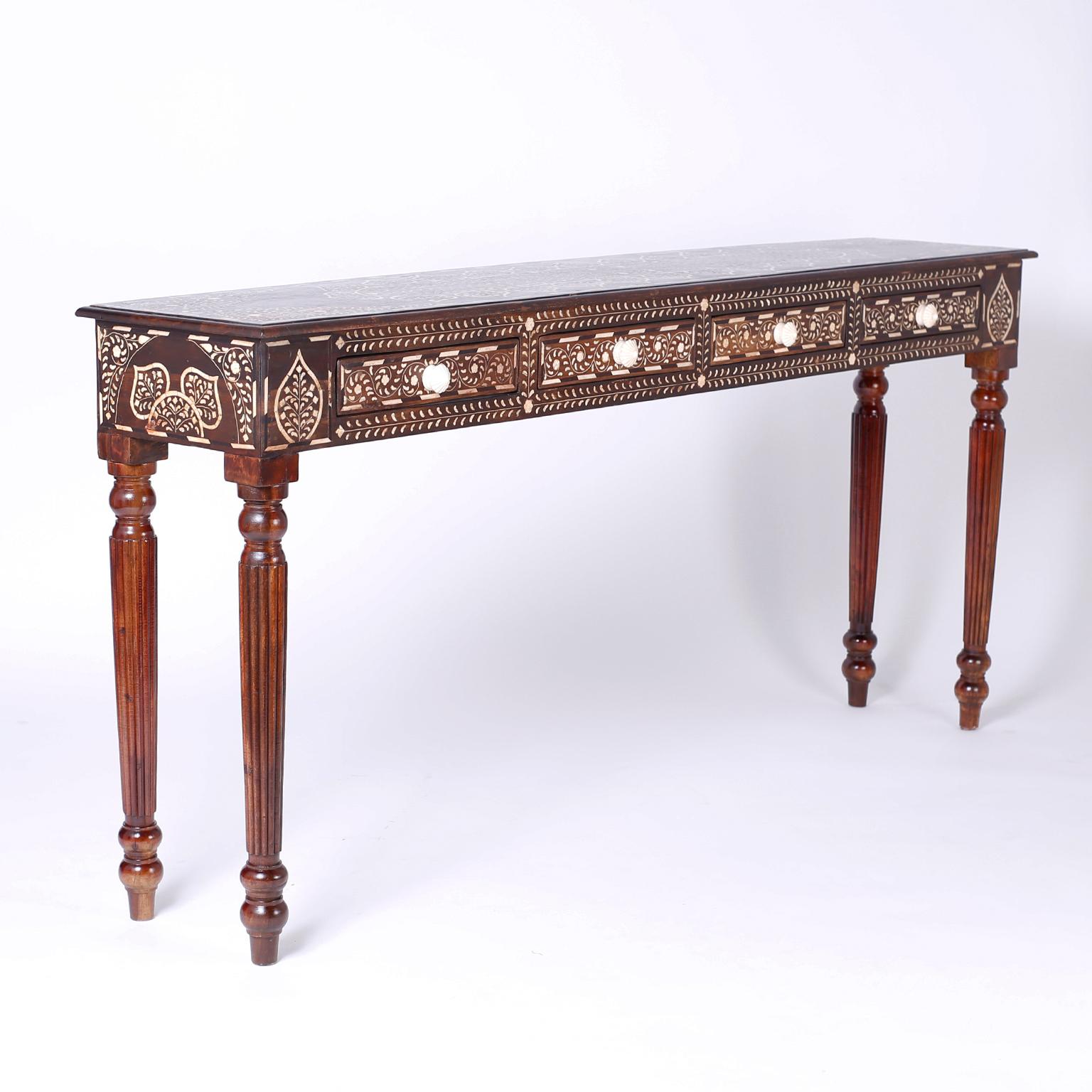 Long and lean Anglo-Indian four-drawer console table crafted in mahogany with exotic floral bone inlays. Featuring a desirable slim profile and fluted and turned legs.