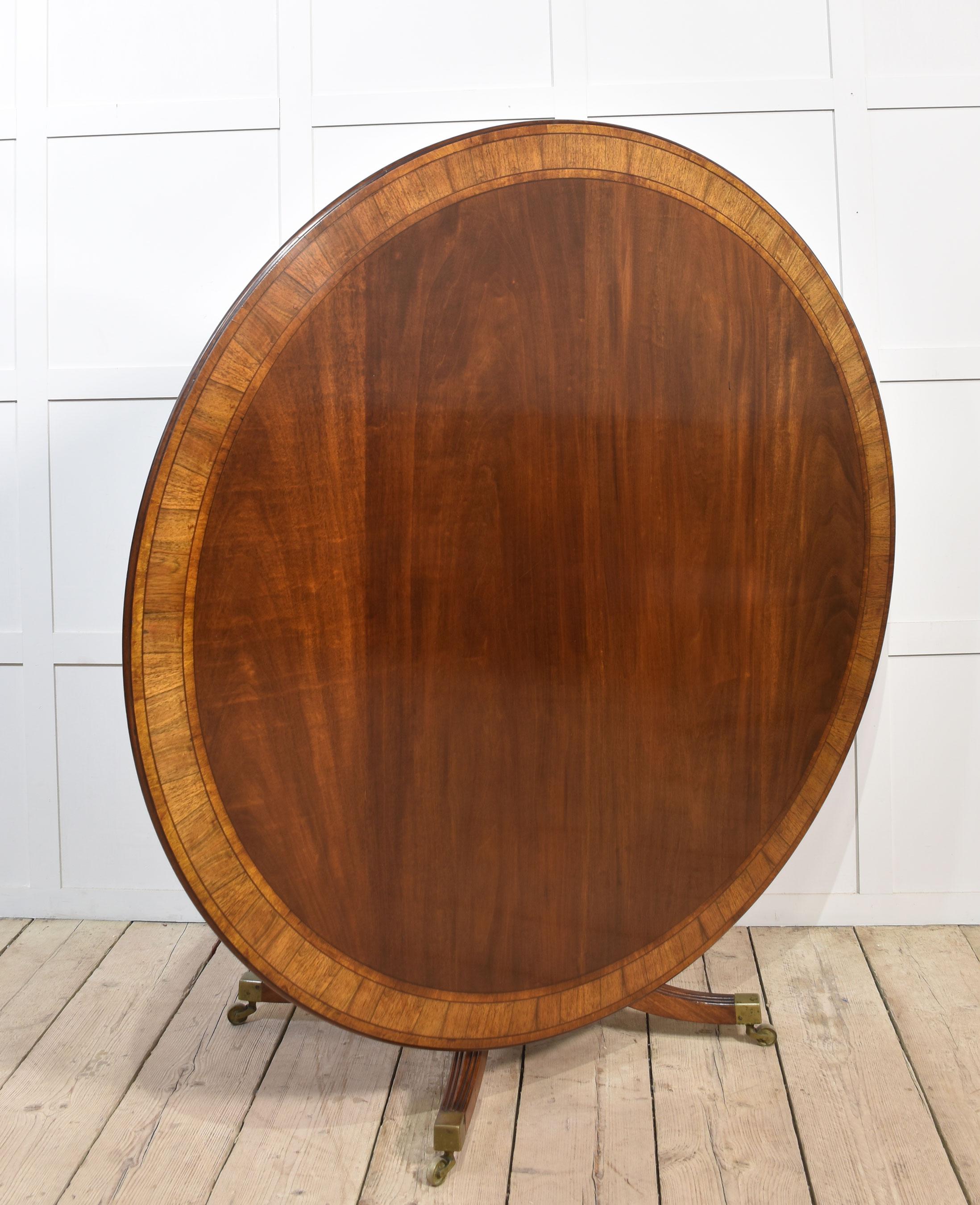 mahogany circular dining table with a well-figured top and a cross-banded edge, it is raised on a column with splayed supports terminating in brass caps and castors. The table will seat 6-8 People and can be dismantled for easy