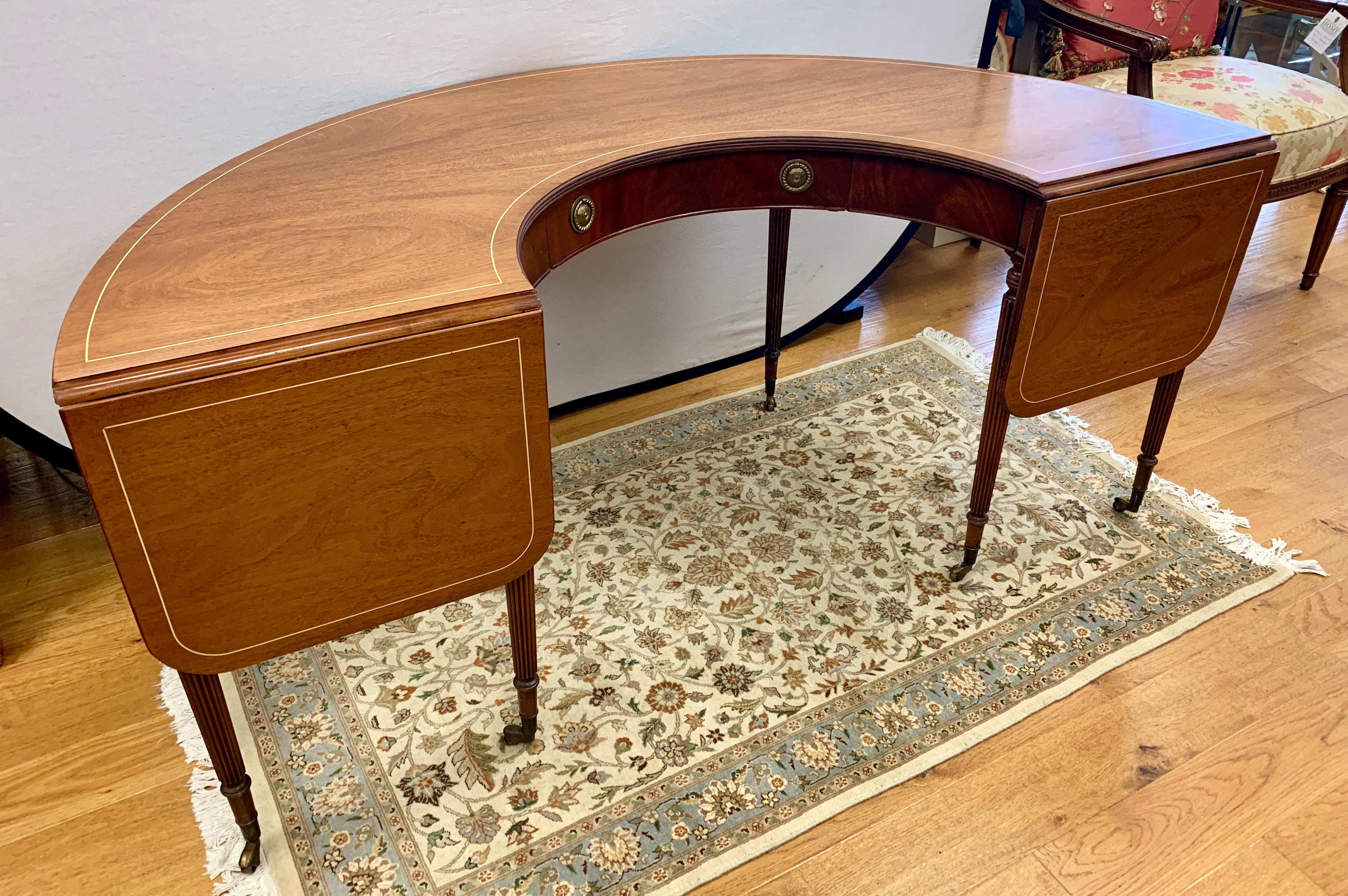 Elegant social mahogany hunt table with half-moon shaped top extendable ends and center drawer. It rests on fluted legs with castors for ease of movement. The dimensions listed below are with the ends folded down. When they are up, add an additional
