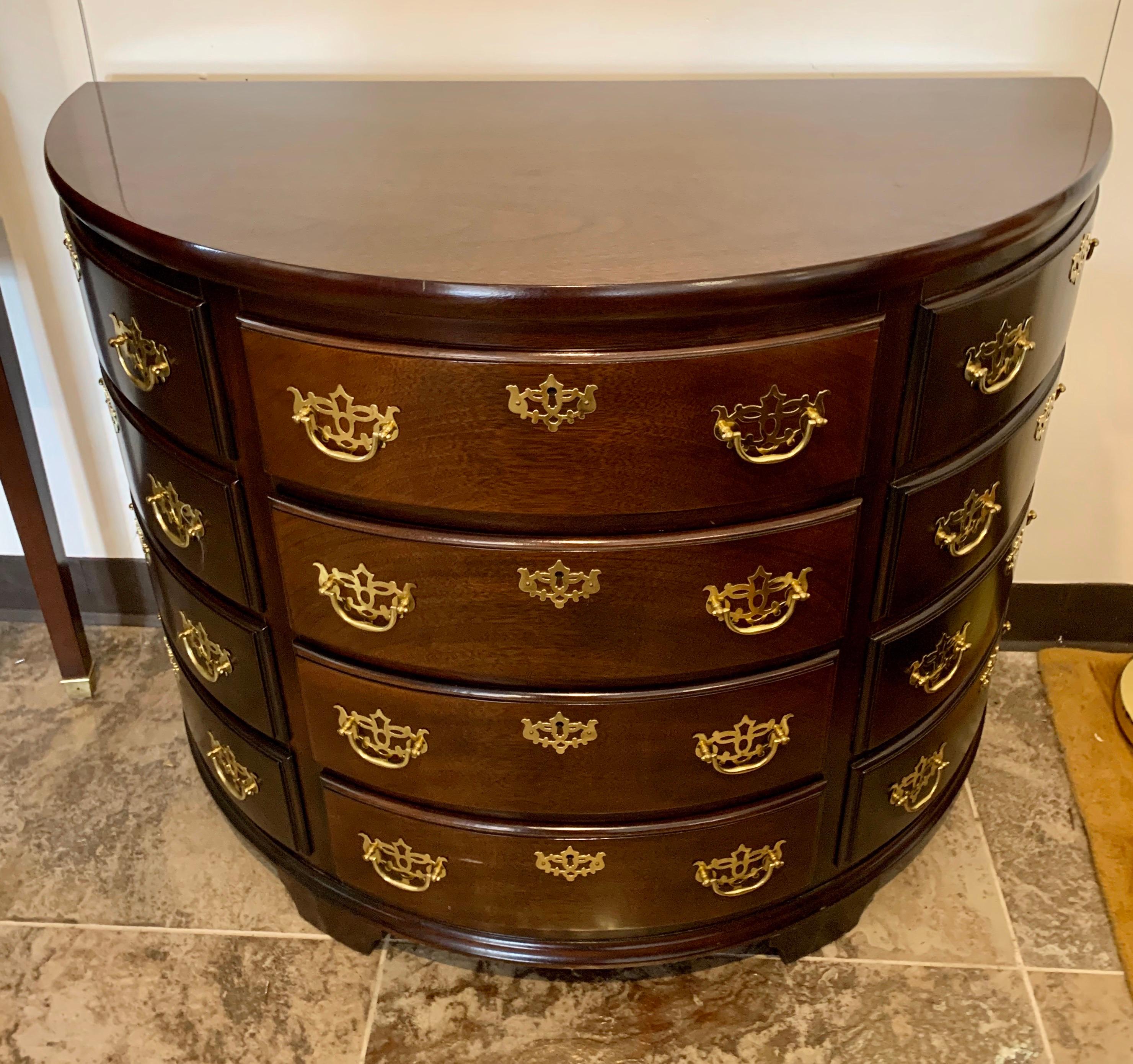 Stunning mahogany demilune chest of drawers with ornate brass hardware. There are four functional drawers and eight faux drawers in all. All dimensions are below. Would make an elegant addition to any room.