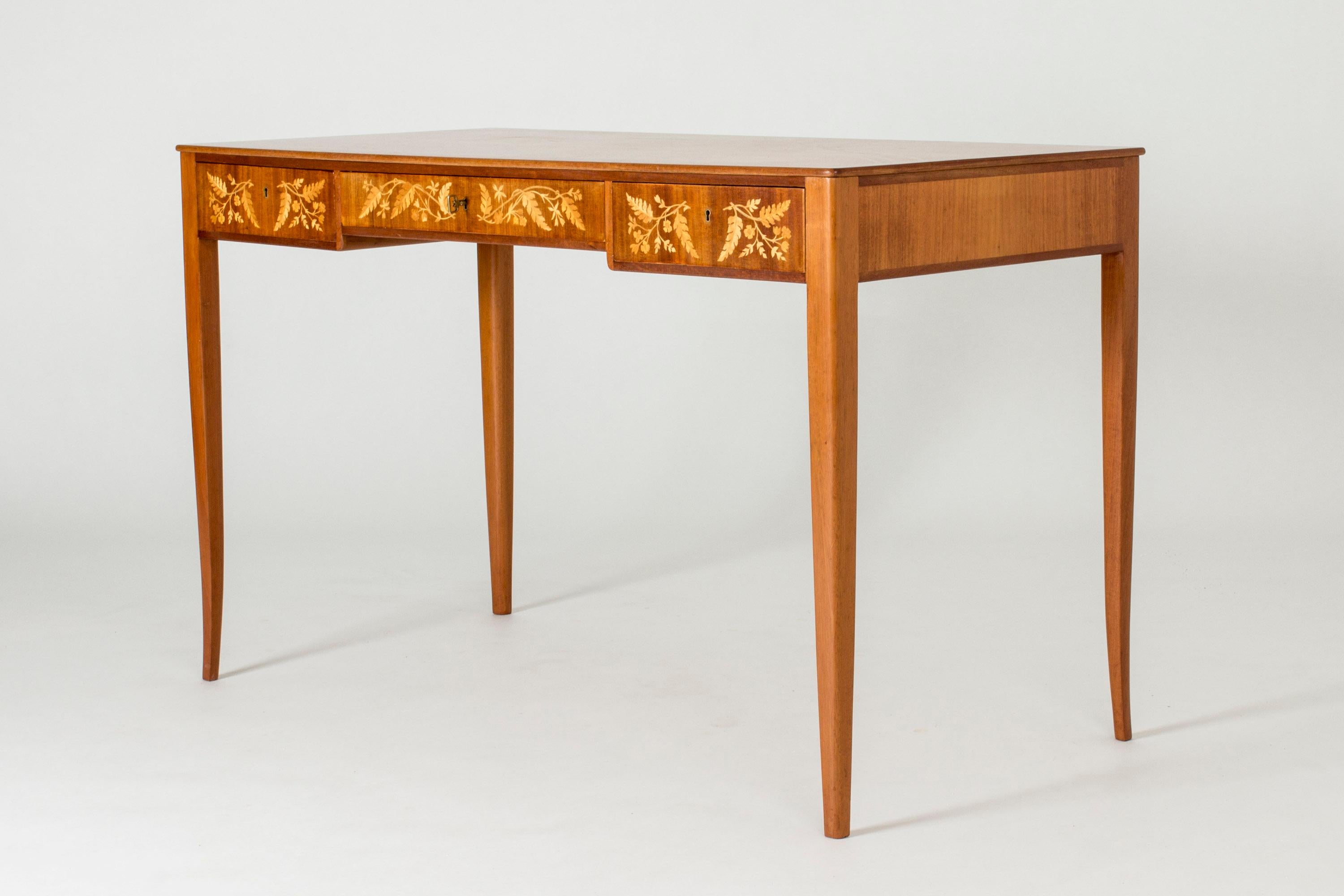 Beautiful small desk by Carl Malmsten, in a light design with slender, subtly curved legs. Lovely inlays of birch in a pattern of flowers and leaves.
