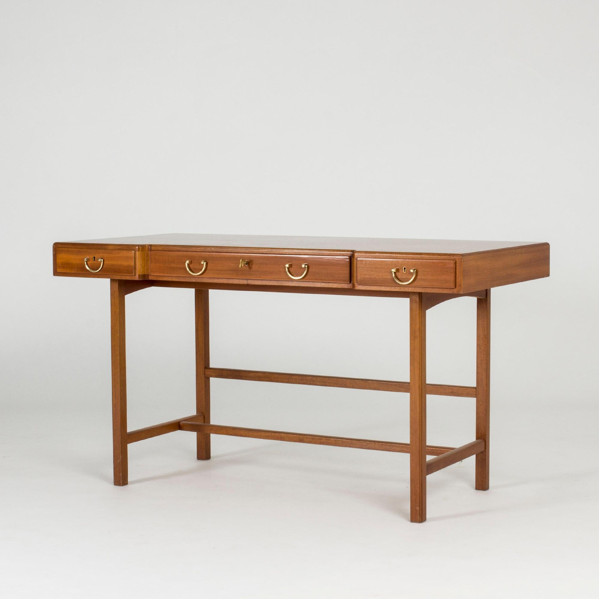 Elegant mahogany desk by Josef Frank with an inlaid stripe of contrasting wood around the edge of the tabletop. Neat row of shallow drawers gives the desk a light expression. Called “Schatull-skrivbordet”.