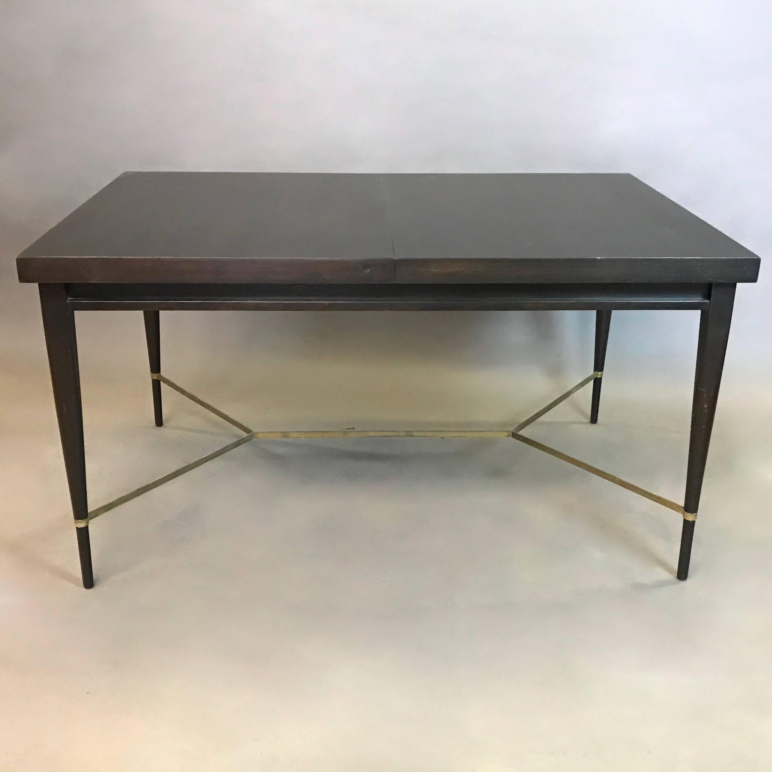 Mid-Century Modern, ebonized mahogany dining table by Paul McCobb for Calvin, Irwin collection features beautifully tapered legs and brass stretcher detail. There are no leaves included. Seats four-six people.