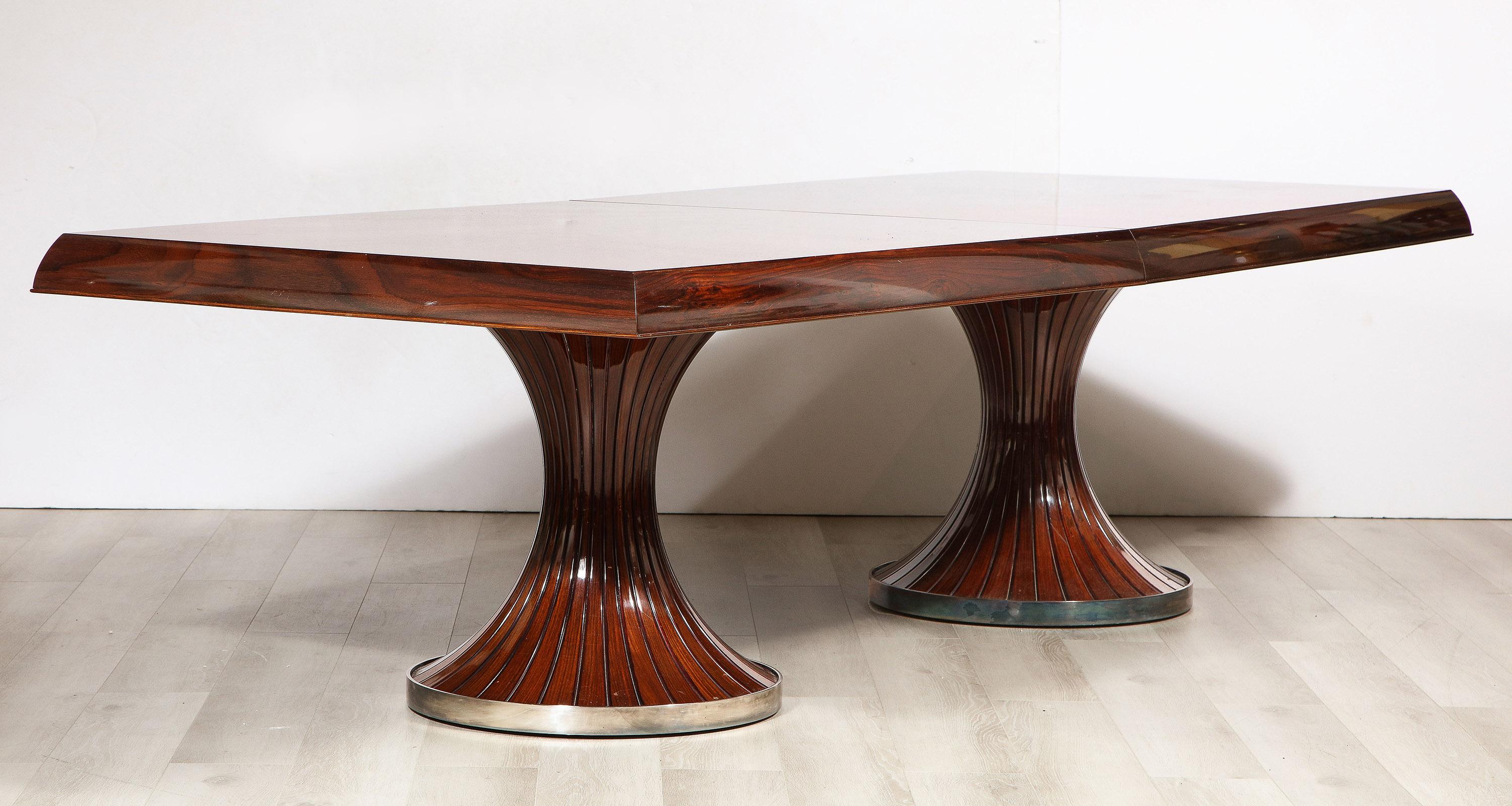 A monumental mahogany dining table, with a star burst cut radiating veneered top with molded edge. Supported by two turned, flared and fluted pedestals with a nickel clad base. Having an additional four matching 30