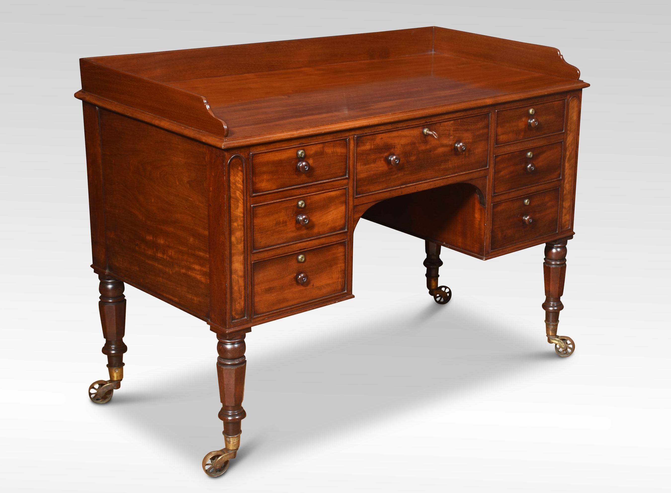 Mahogany Dressing or Writing Table, the rectangular top with a raised three-quarter gallery, above an arrangement of drawers with turned knob handles. All raised up on four fluted tapering supports with original brass caps and