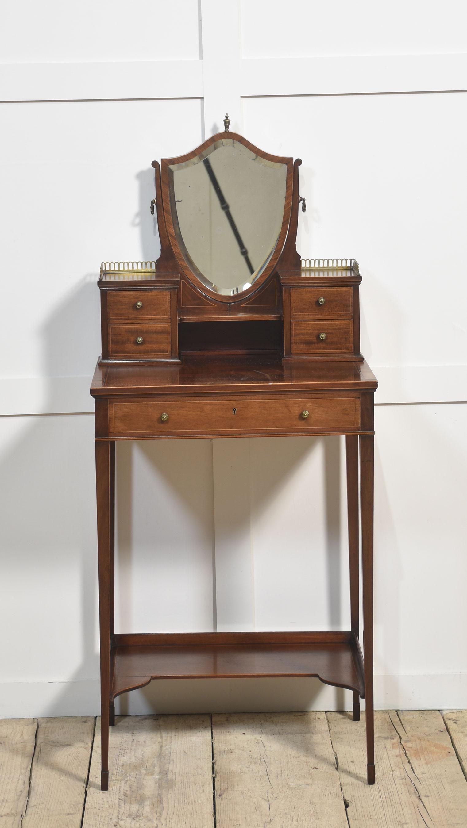 Coiffeuse en acajou de petites dimensions, miroir biseauté en forme de bouclier. Flanqué de tiroirs courts de chaque côté au-dessus du plateau en acajou figuré. La partie inférieure est équipée d'un tiroir central, le tout reposant sur des pieds