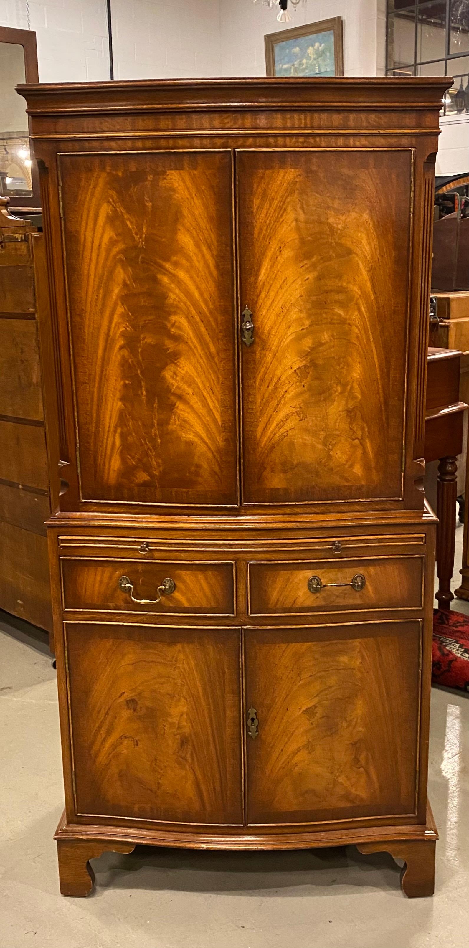 A mahogany dry bar or drinks cabinet crafted in mahogany, Georgian styled with a delicate serpentine curve to the front to give it a classic line. Beautiful interior of mahogany with two shelves displays what needs to be displayed. The pull out