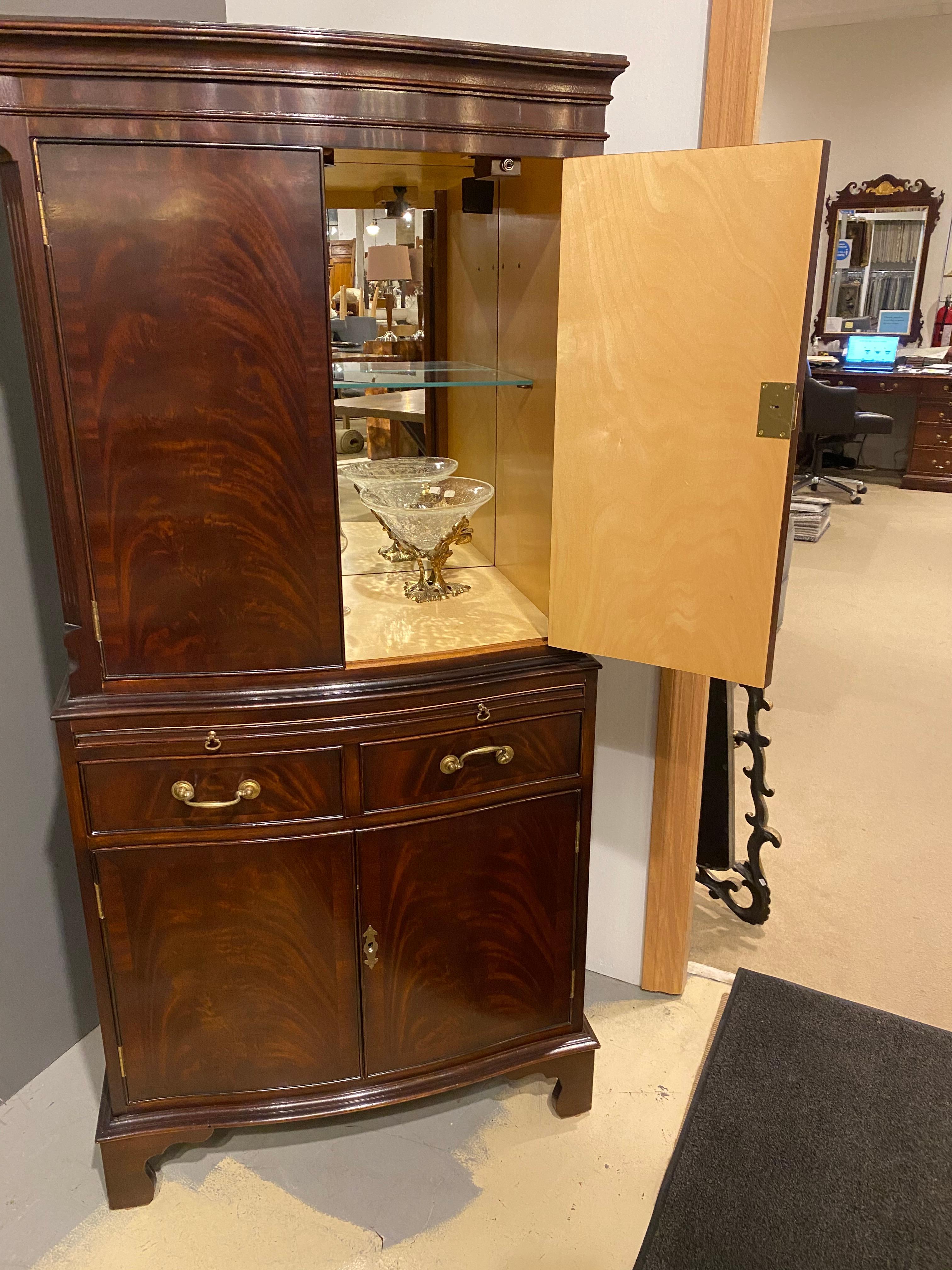 A mahogany dry bar or drinks cabinet crafted in mahogany, Georgian styled with a delicate serpentine curve to the front to give it a classic line. Beautiful contrasted interior of sycamore with a mirrored back and glass shelf displays what needs to