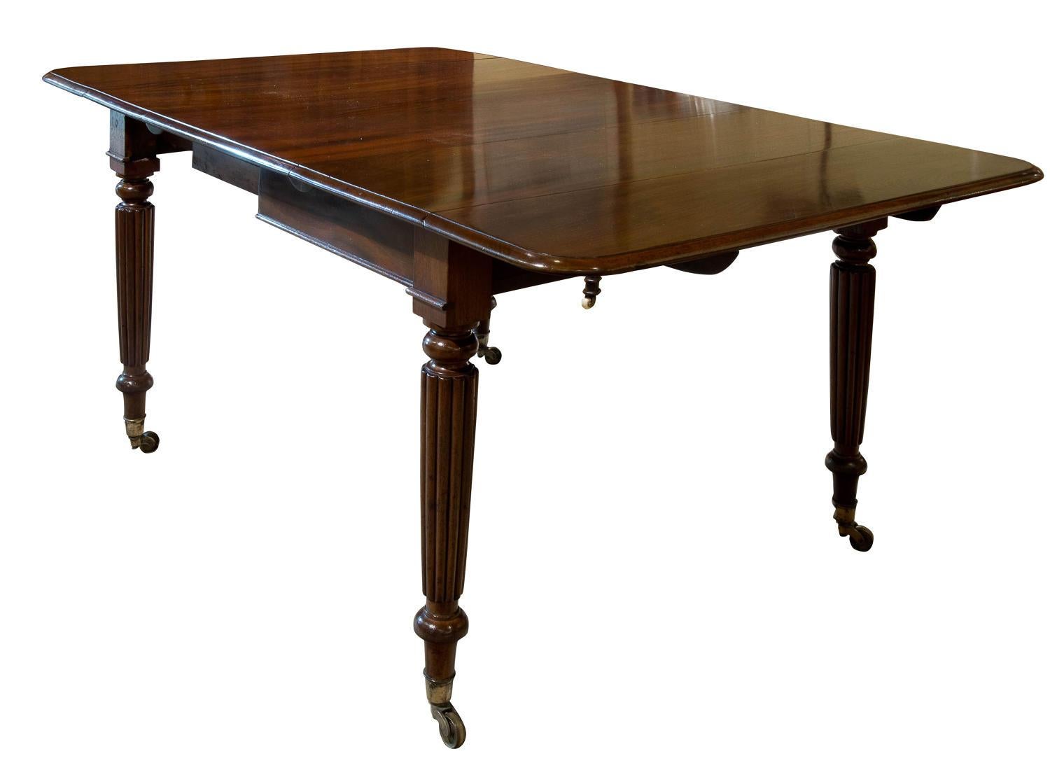 Mahogany drop-leaf dining table on reeded legs and brass castors,

circa 1830.

Width 167cm when open.