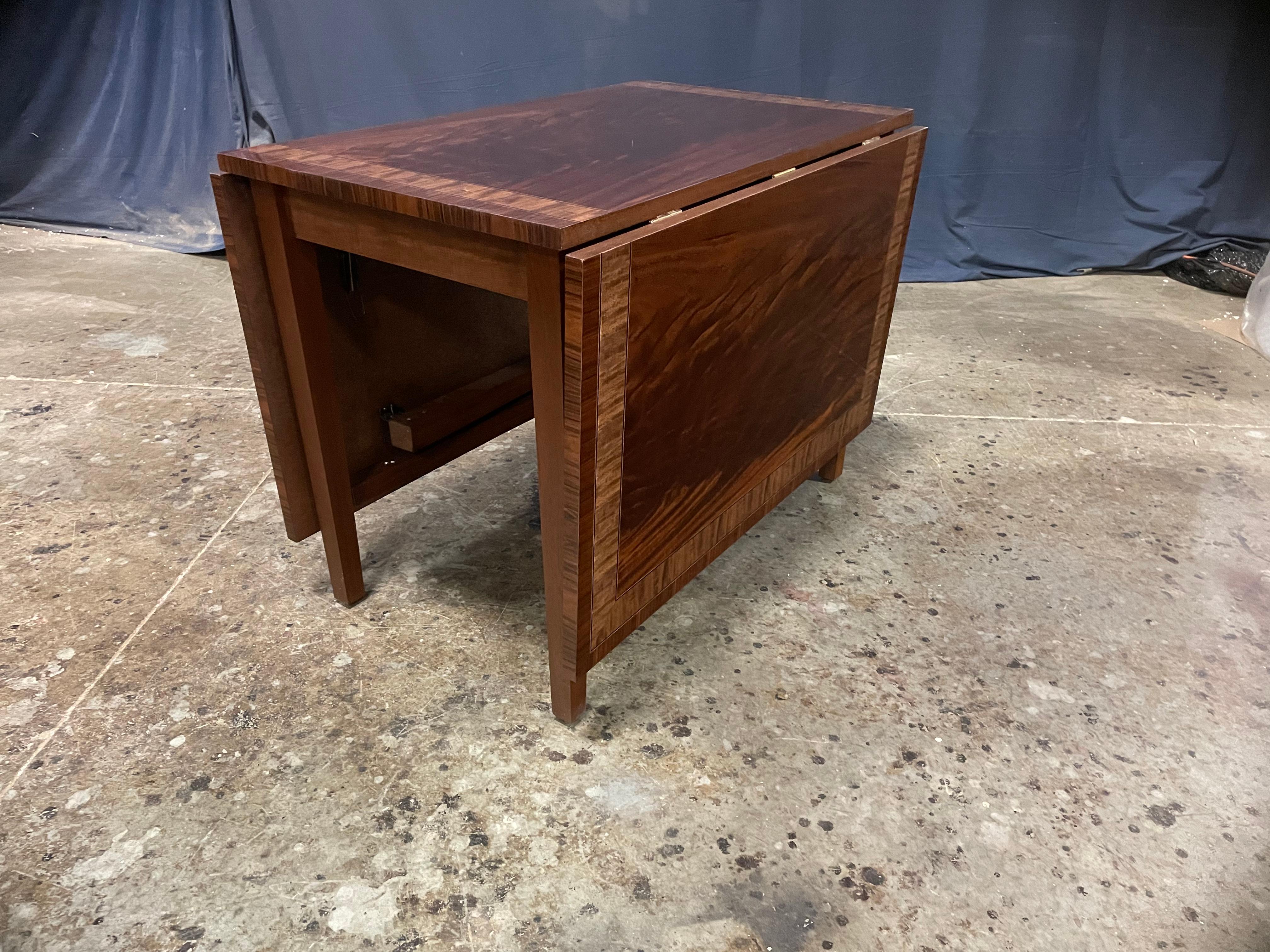 This is a mahogany drop-leaf table made in the Leighton Hall shop. It is ideal for the dining area of an apartment or condo or in a breakfast area. It features a field of swirly crotch mahogany with Pau Ferro and Satinwood borders. The legs are made
