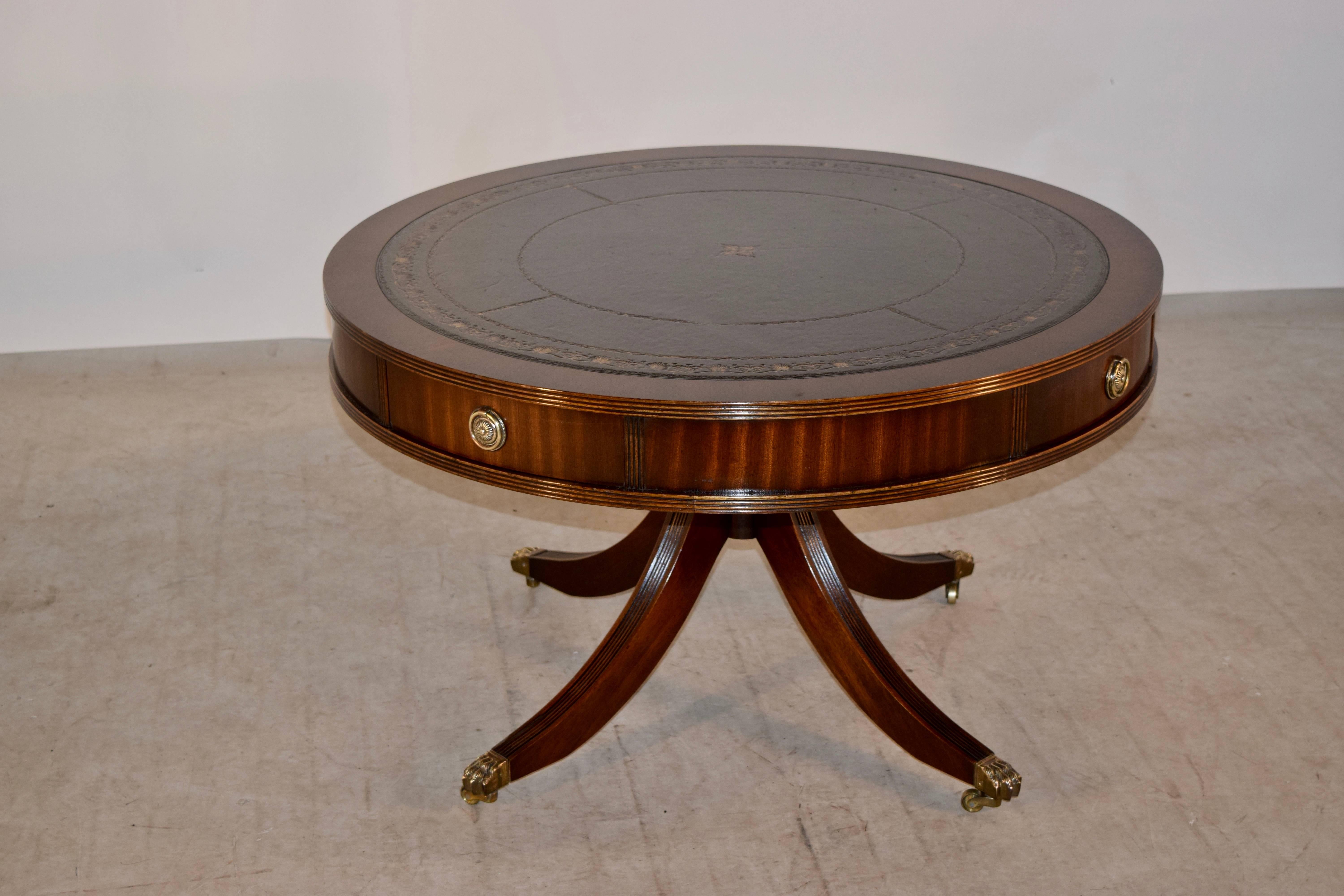 Mahogany coffee table from England, circa 1950. The top is banded in mahogany and has a central panel of hand tooled leather in dark green. The top has a reeded edge on the top and bottom and has drawers which open to reveal storage. This drum style