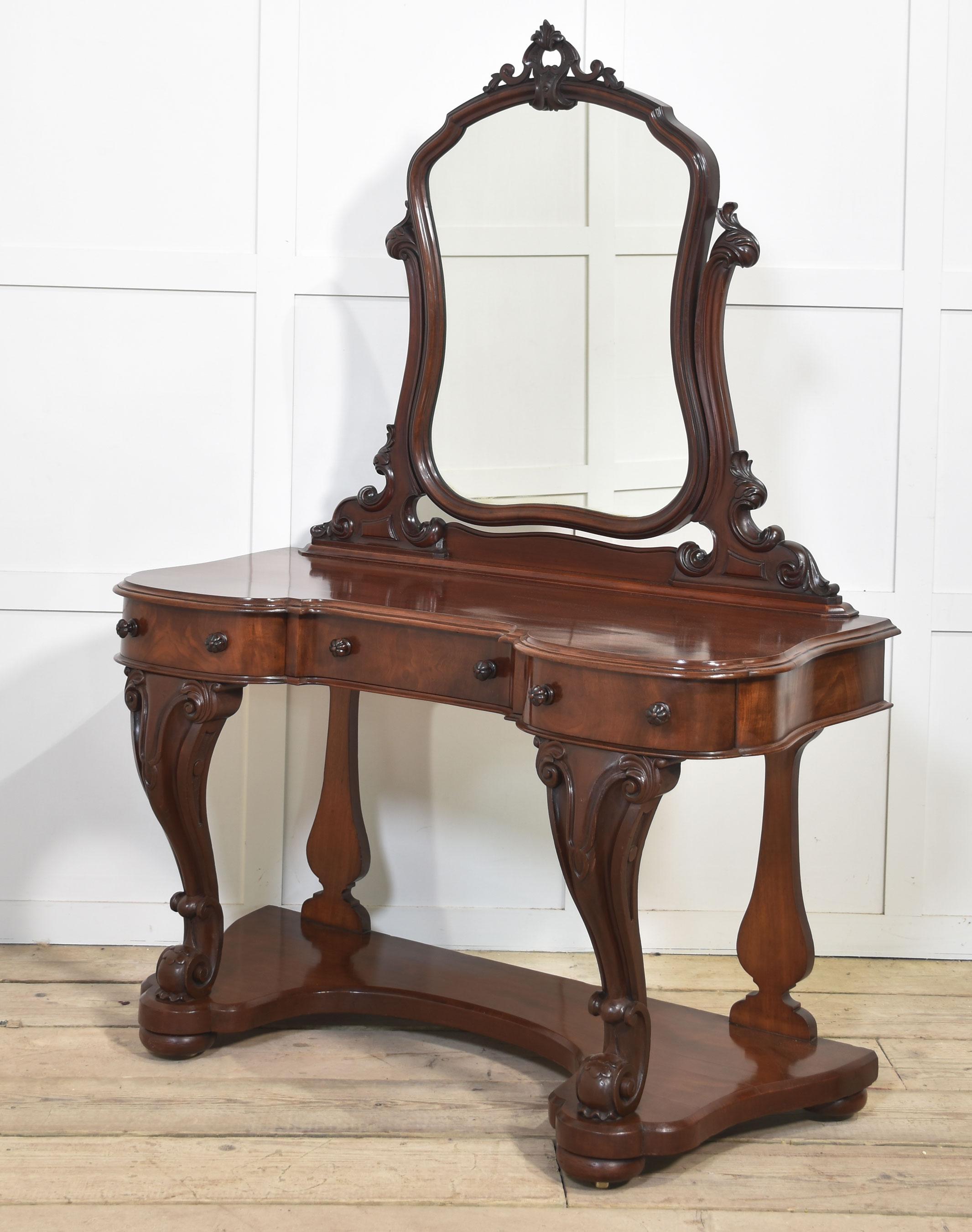 Mahogany duchess dressing table, the original mirror plate in the moulded frame between carved supports, To the base with a large mahogany top above an arrangement of freeze drawers. All raised on carved cabriole front supports united by a shaped