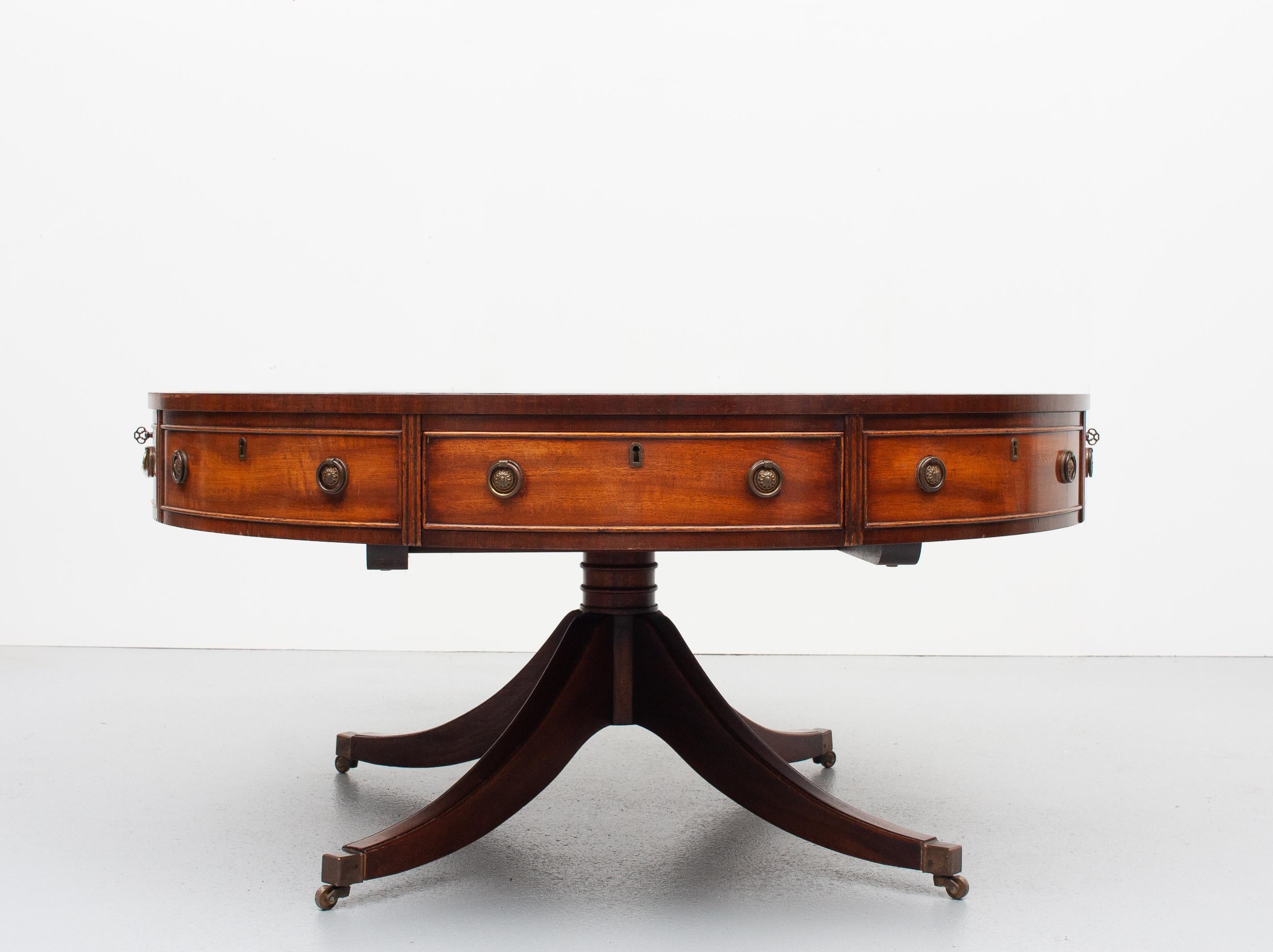 Love this exceptional good looking English drum table.  Bevan Funell Produced by Reprodux  .Wooden gold embossed brown leather top. Sold by Harrods London  
4 drawers two original keys. Brass wheels. Just the right amount of patina. Very good