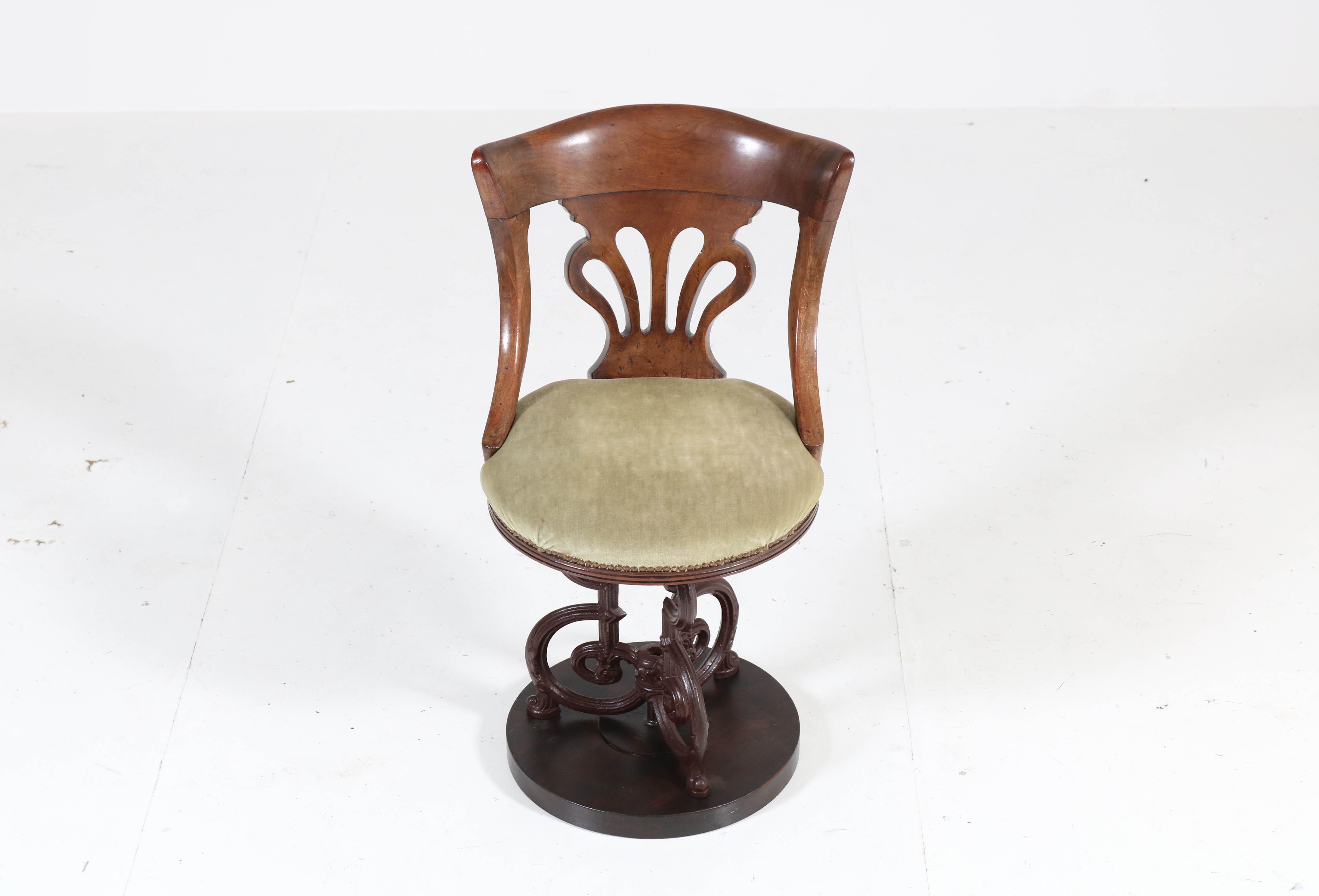 Stunning and rare nautical captains swivel chair.
Striking English design from the 1880s.
Solid mahogany on an original cast iron base.
The tufted round seat is upholstered with green velvet.
In good original condition with minor wear consistent