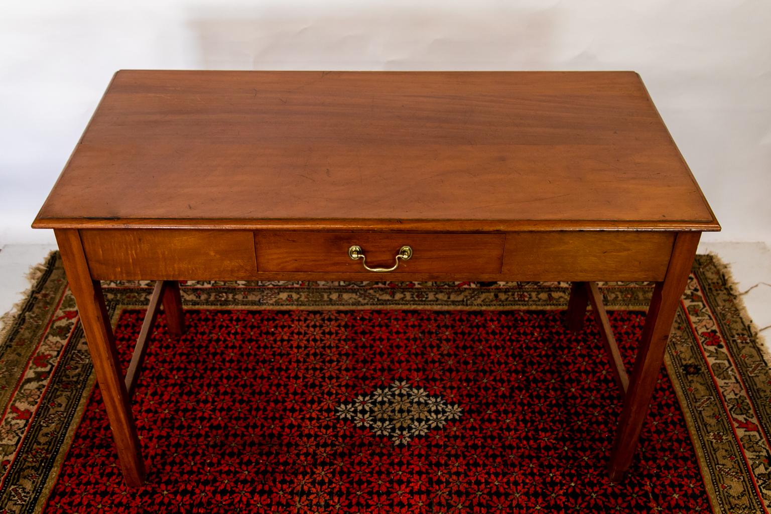 This table is solid mahogany. The top has a bullnosed edge. The four legs have pencil post chamfers on all four sides and are joined by a stretcher on the sides and back.