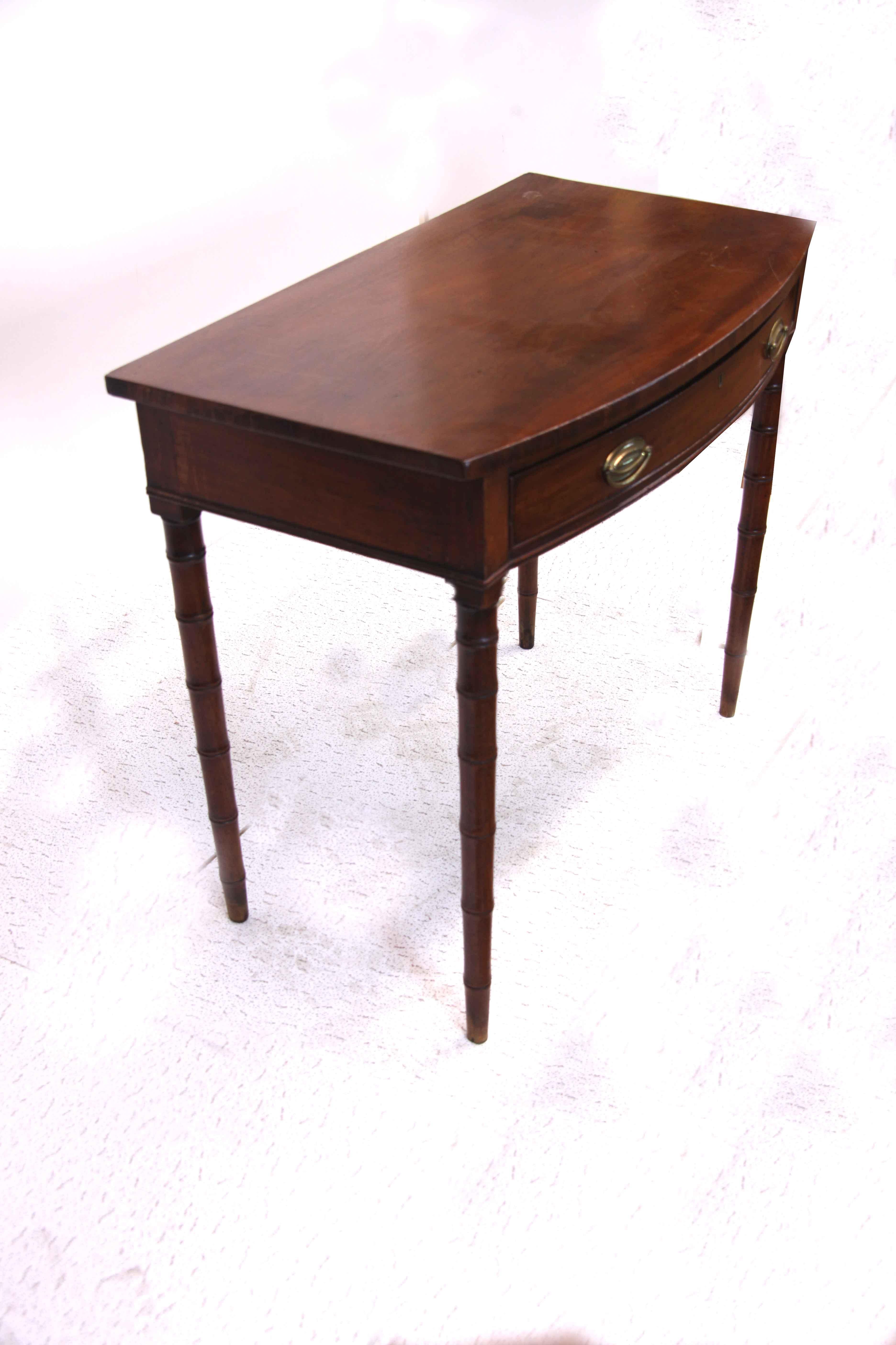 Mahogany faux bamboo bow front table, the one drawer has oval brass pulls ( hand made but not original) , the top has a nice warm color and patina, the tapered leg with crisp bamboo turnings. We do not use the term ''rare'' lightly; we have had