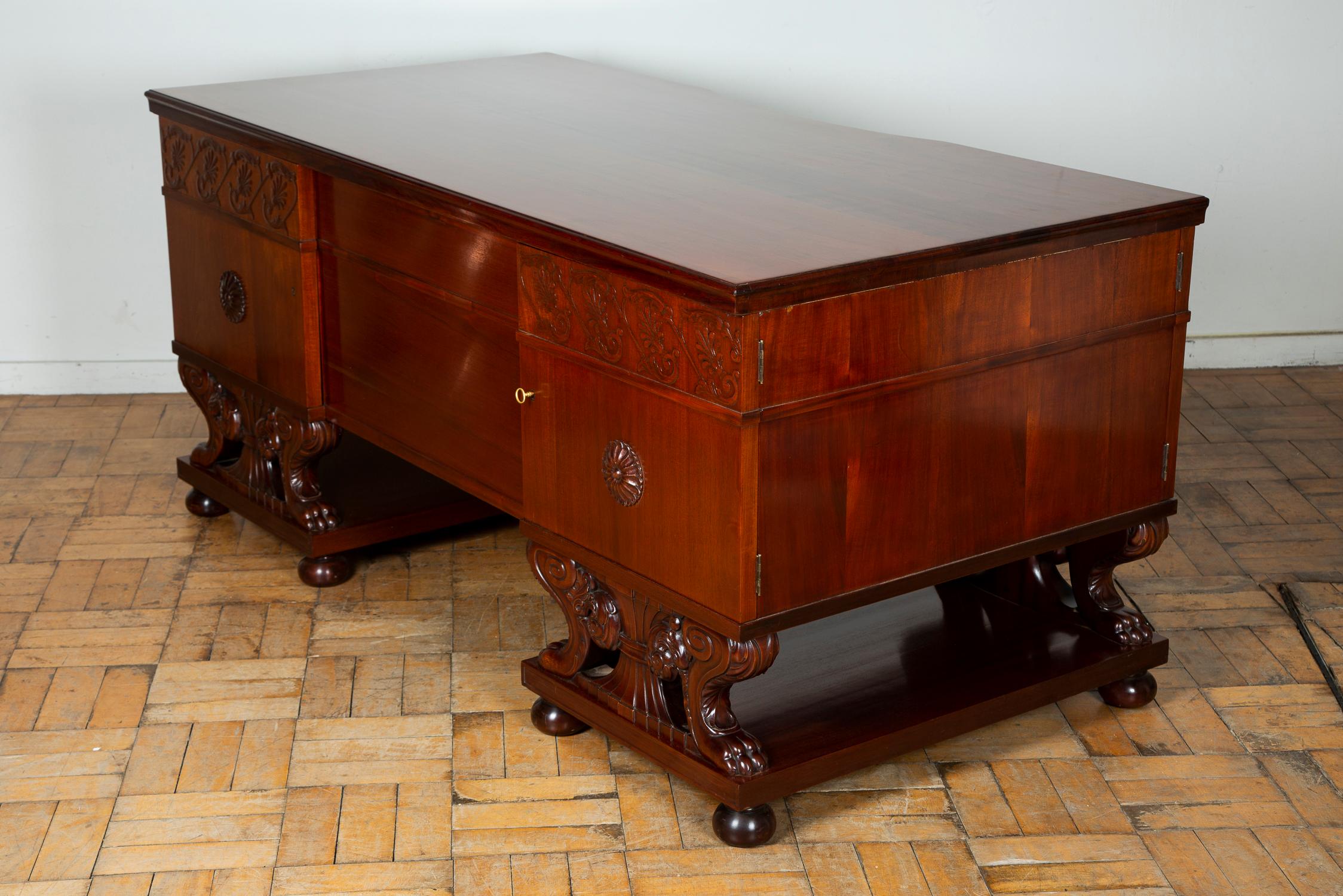 A freestanding mahogany desk attributed to Lysberg and Hansen.

The desk is finely carved with floral motif and rosettes to each pedestal, the central drawer has a reeded pattern with a classical urn in the middle with the key hole.

Each