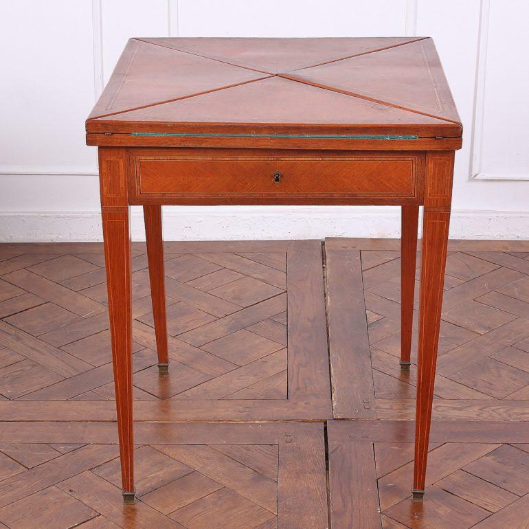 English Edwardian mahogany fold-open ‘envelope’ games table with cross-banded inlay to the top and boxwood stringing and banding to the skirt and square-tapering legs. Newly-installed green baize playing surface. 

23.5 inches Wide (Closed) x 47