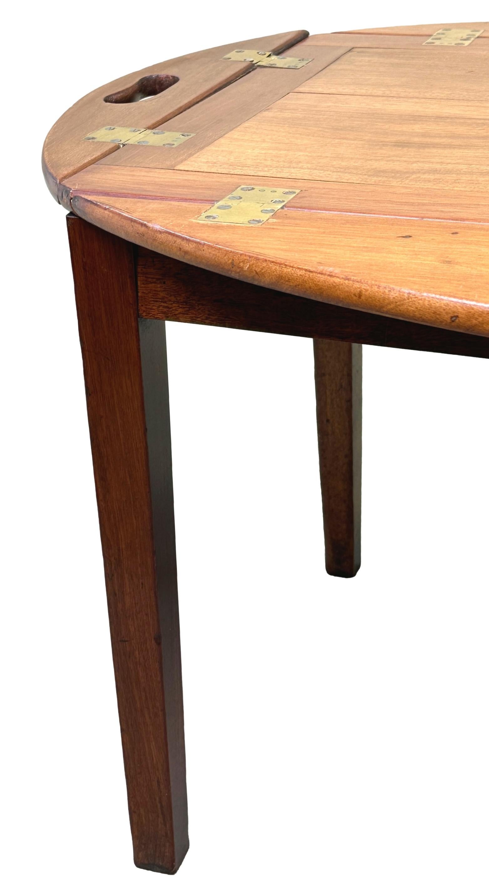 A Good Quality And Elegant Late 18th Century, Georgian Mahogany Oval Butlers Tray, Of Panelled Design, Having Original Brass Hinges And Pierced Handles To Folding Sides, Raised On Later Square Tapered Leg Mahogany Stand.


During the 18th and 19th