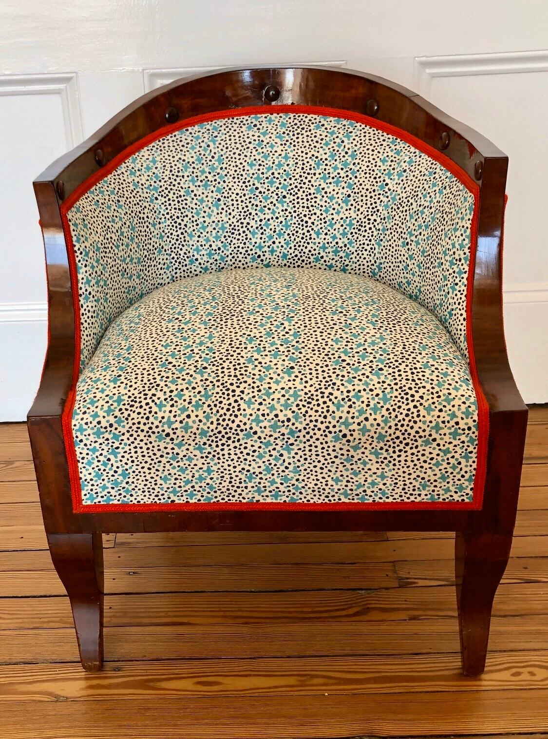 Dramatic German mahogany Biedermeier chair has a robust curved back with seven mahogany turned buttons on the crest rail. The crest rail curves round to sweeping concave arms continue down pass the seat rail to stylized saber legs. 

Seat height