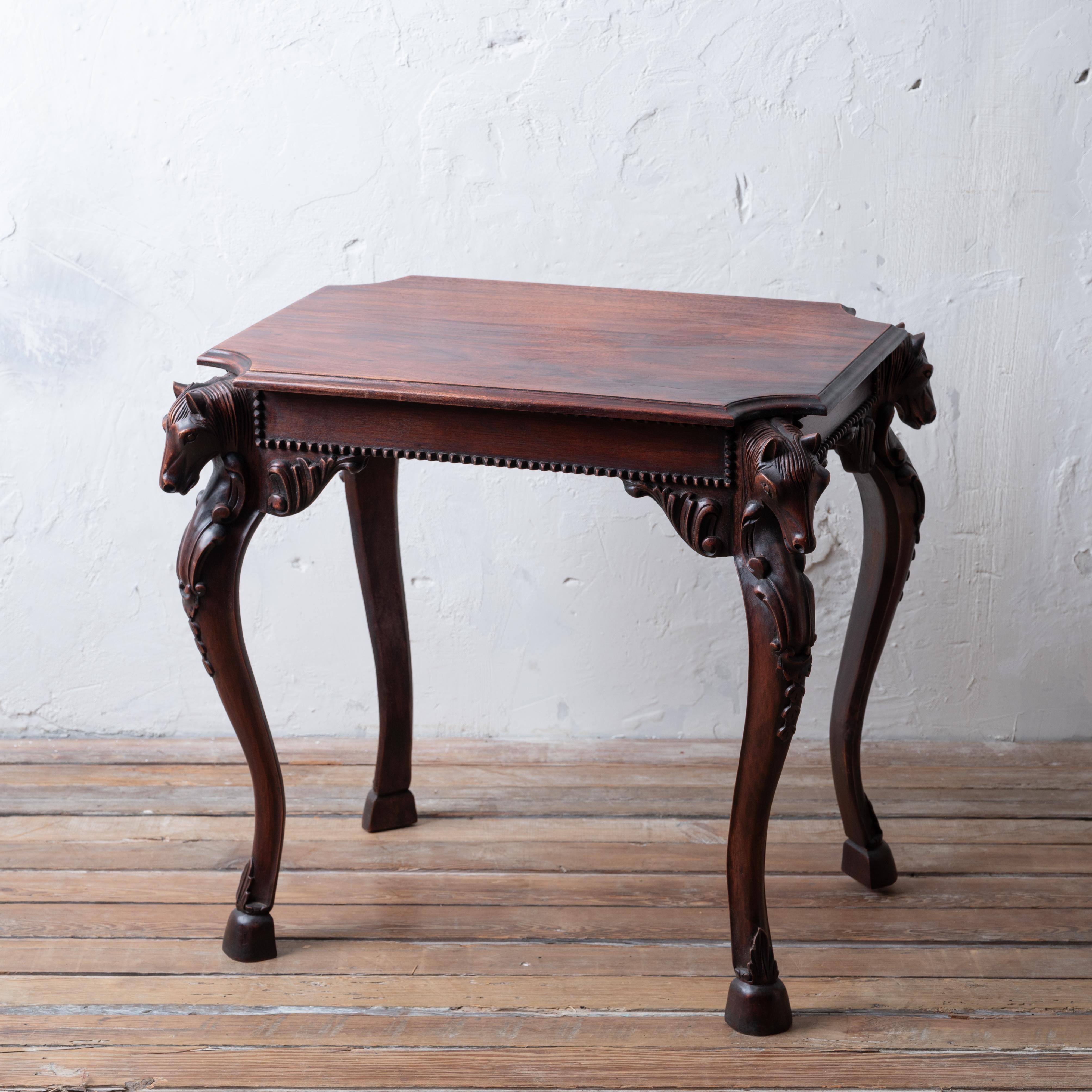 A carved mahogany horse head side table, late 20th century.

28 inches wide by 19 ½ inches deep by 26 ½ inches tall

