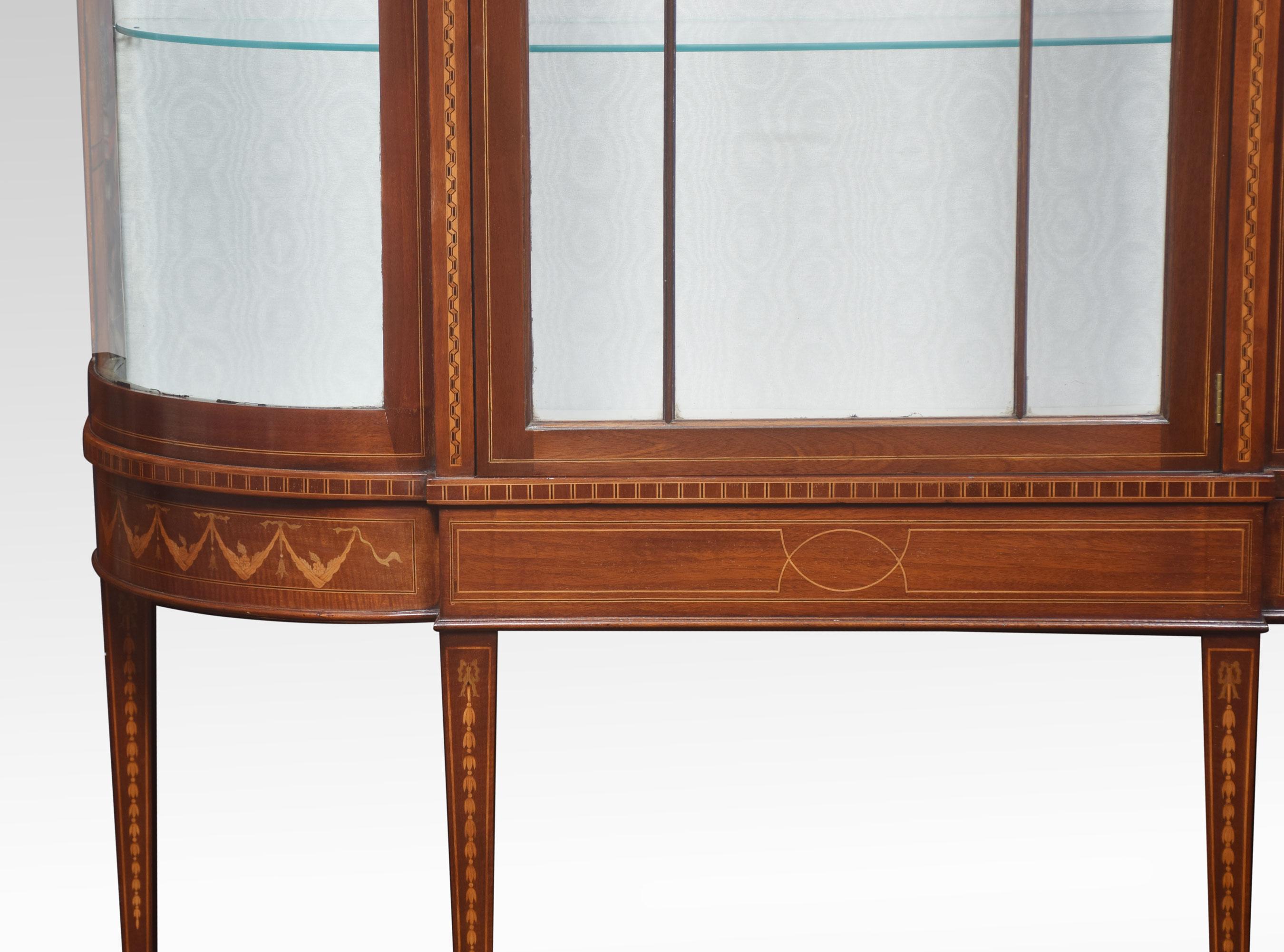 Mahogany bow fronted display cabinet the molded cornice above large central single door opening to reveal the upholstered interior and two glazed shelves. All raised up on tapering legs united by under tier.
Dimensions
Height 75 inches
Length 50
