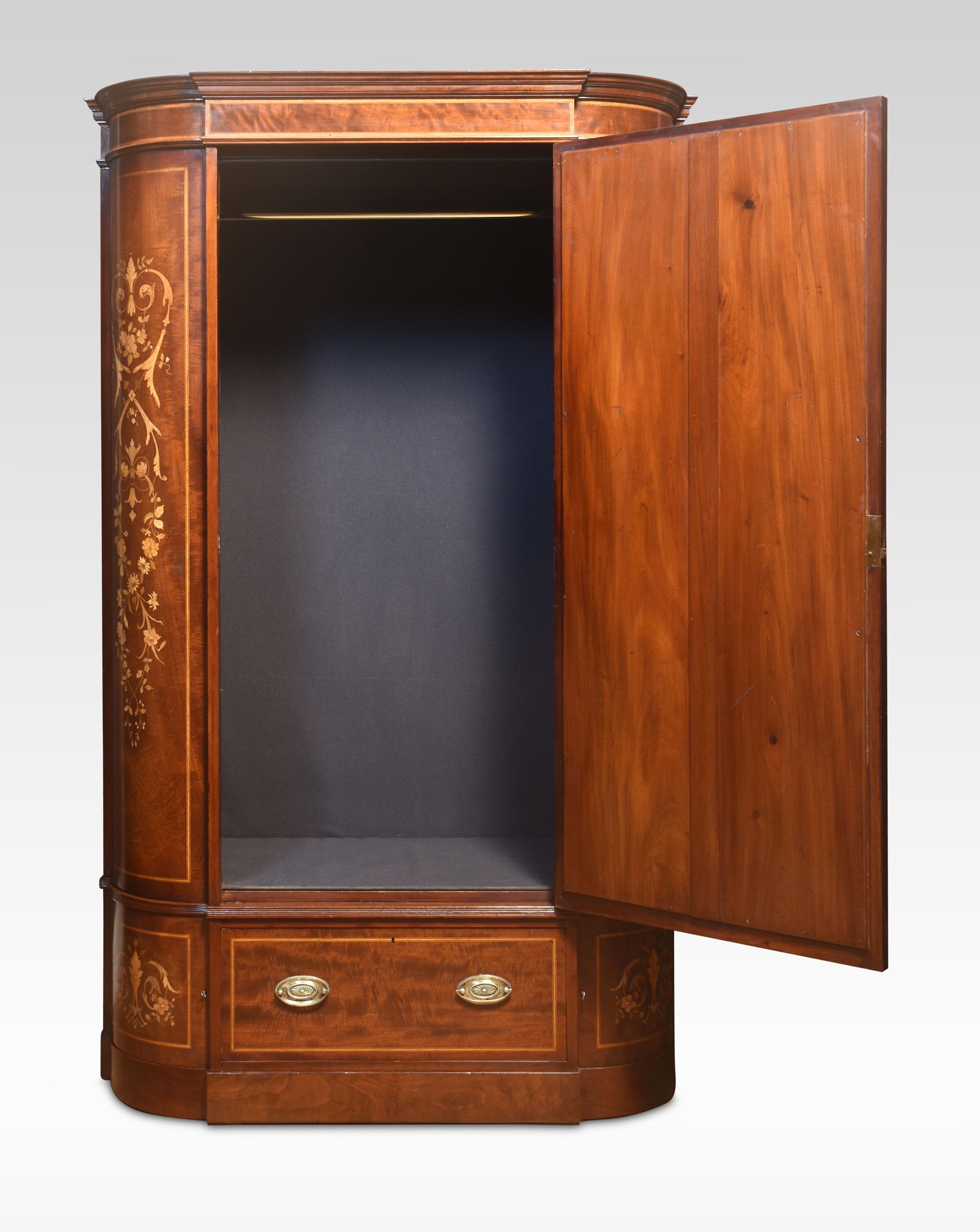 Early 20th-century mahogany and marquetry wardrobe, having moulded cornice above the central bevelled mirror door opening to reveal large upholstered hanging area. Flanked by marquetry decorated quarter bowed panels. The base section is fitted with