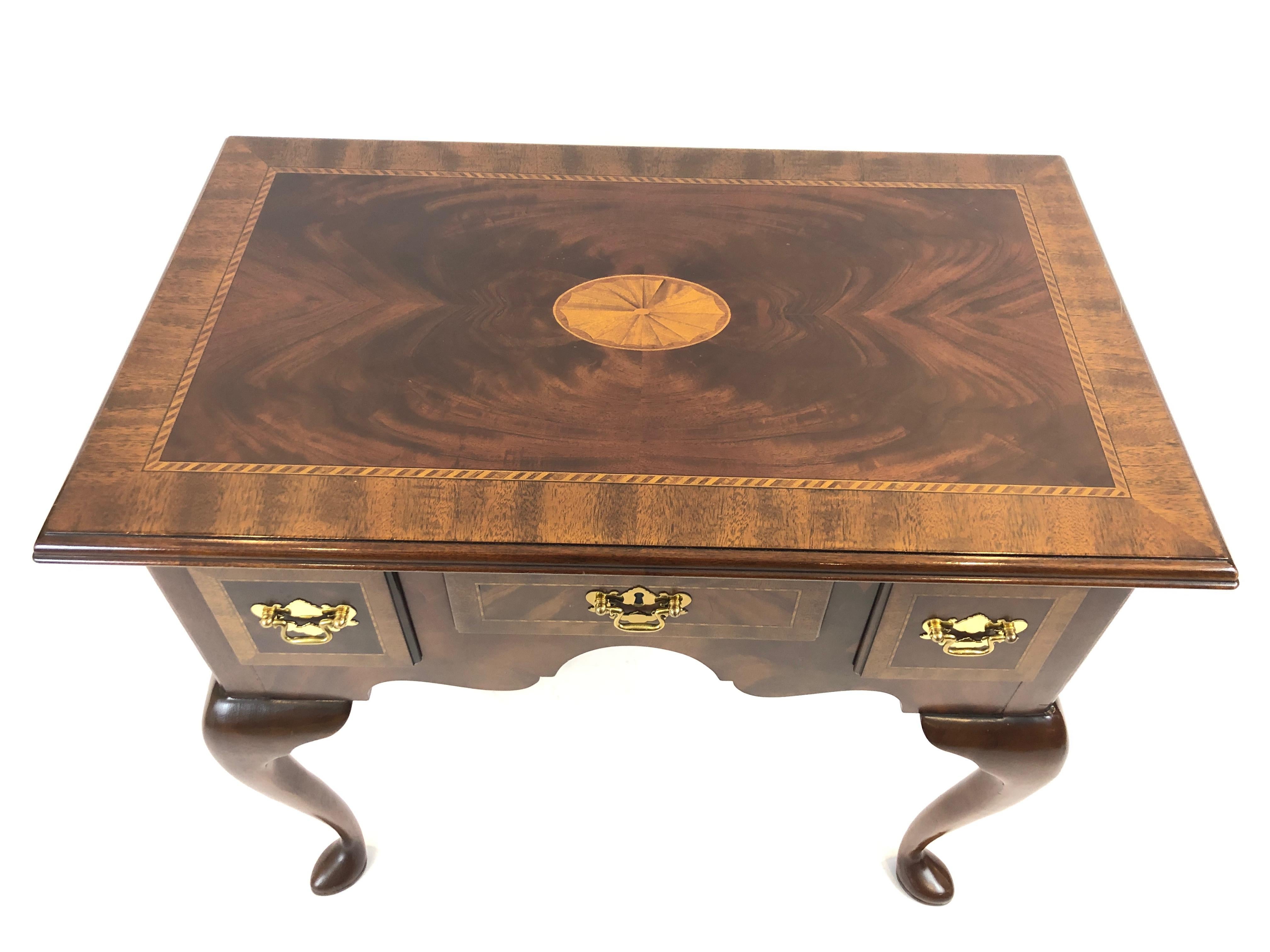 A handsome traditional style flame mahogany inlaid low boy or small console with 3 drawers having lovely satinwood fan design in the center of the top, Chippendalesque brass hardware, and cabriole legs terminating in pad feet.