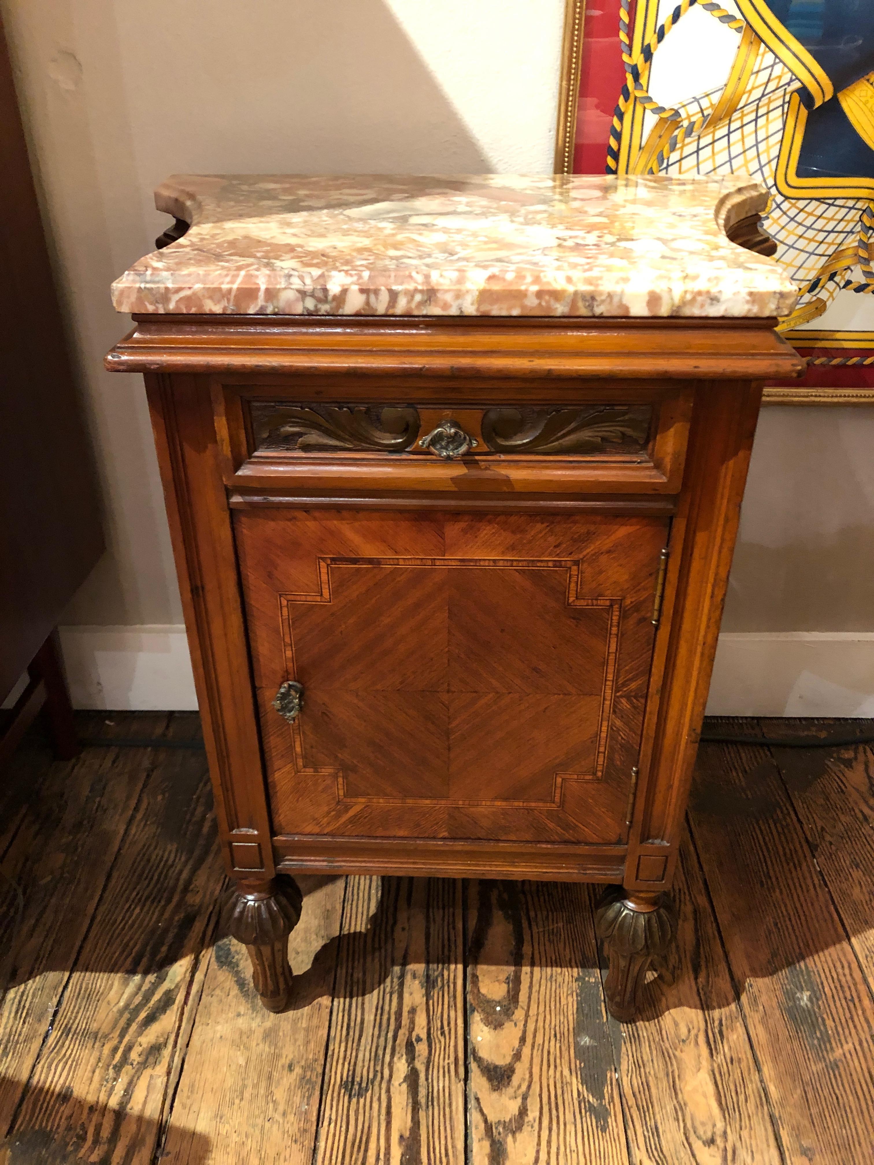 A perfect size single night stand or end table having a scalloped cream and rust colored marble top, lovely carved and inlaid mahogany base, drawer and panel door with storage inside. Very pretty feet with carved spheres.