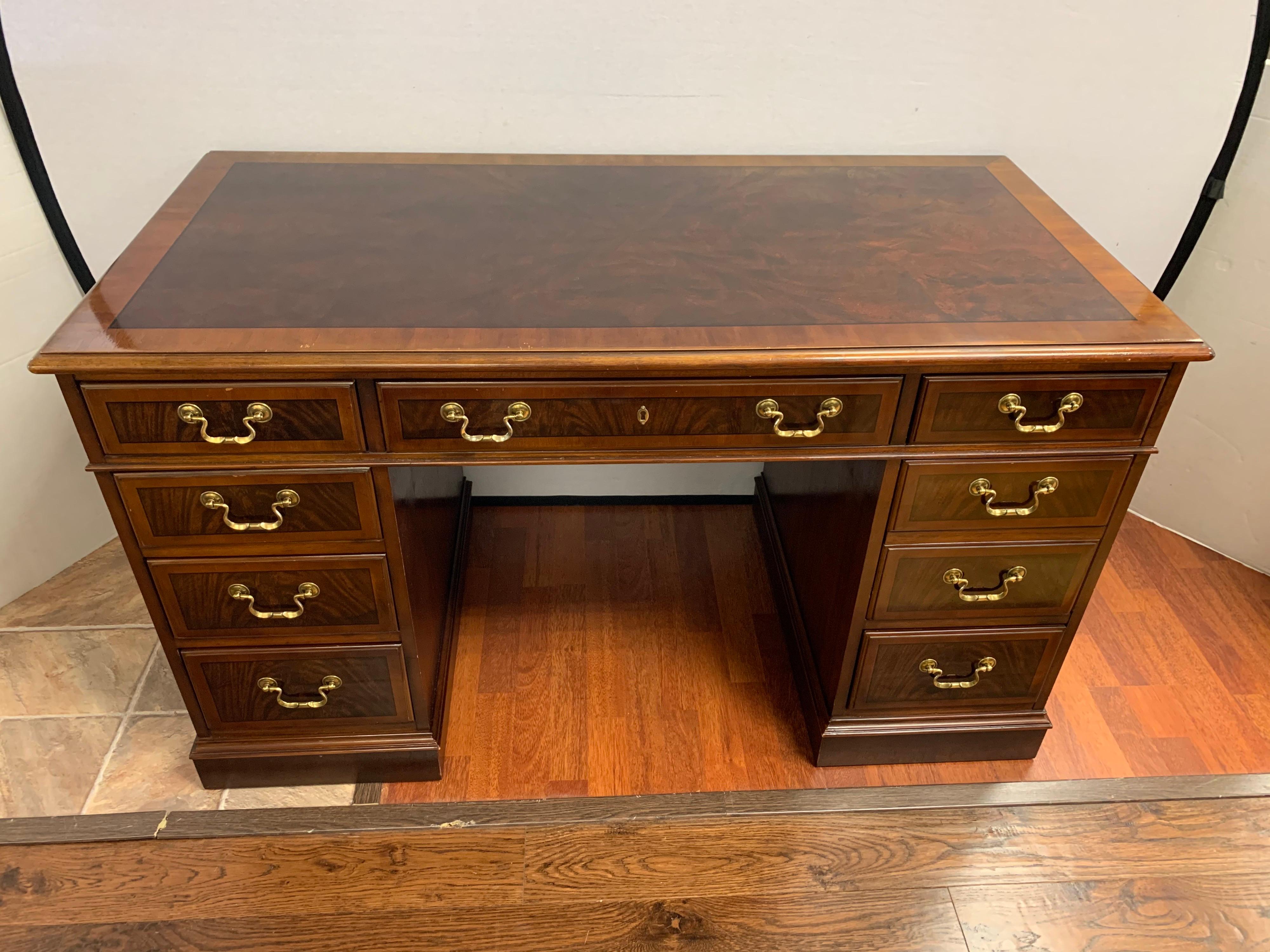 Elegant nine-drawer, signed Drexel mahogany and brass kneehole partners desk. Features a banded inlay on top and drawers.
Produced by one of the preeminent US furniture makers, Drexel. Dark mahogany finish is offset by real brass hardware