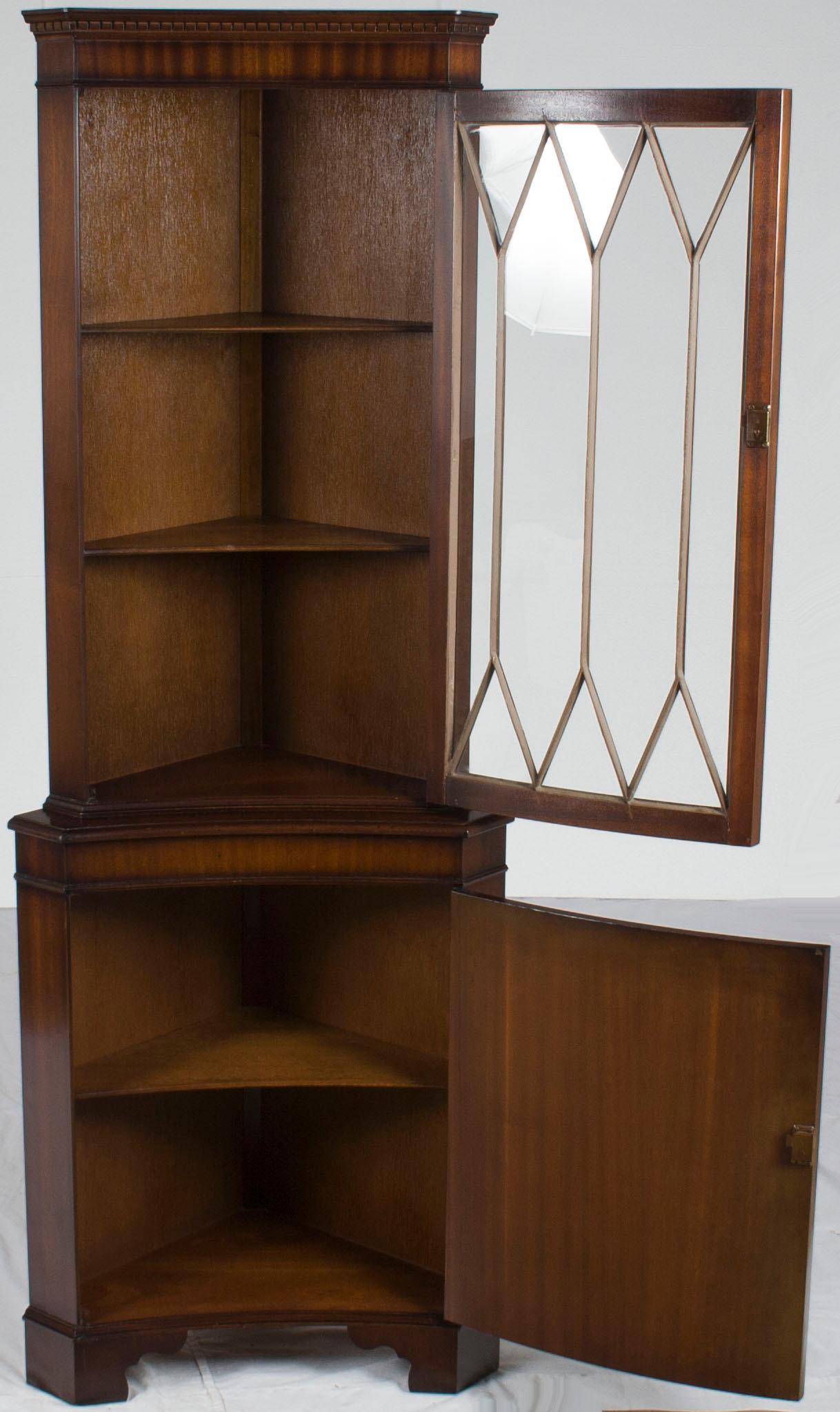 This beautiful antique corner cabinet was English-made around 1960, and today it remains as beautiful as ever. The mahogany displays a fine grain and a rich complexion, particularly on the lower cabinet door where flame mahogany was used. The