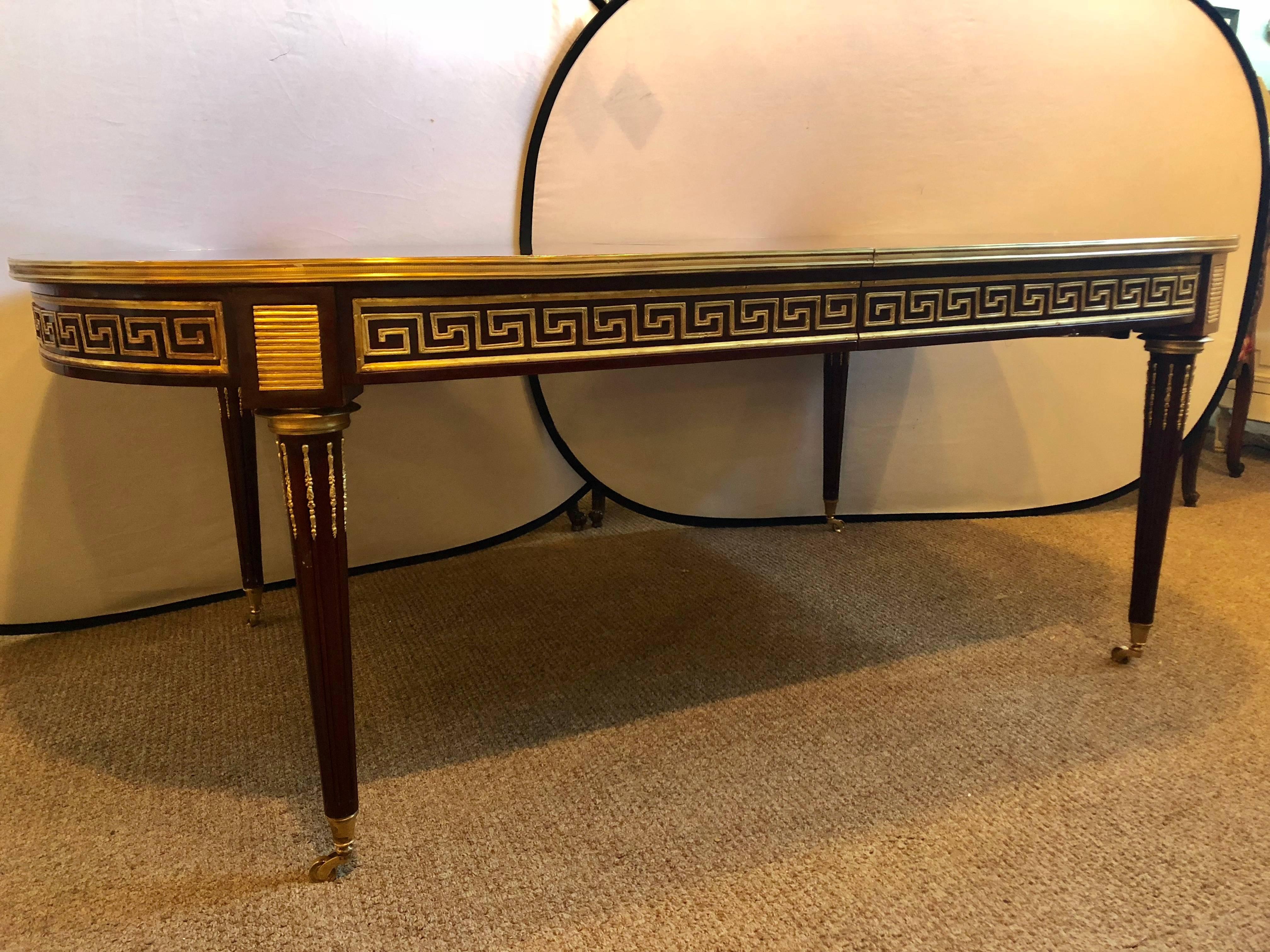 Hollywood Regency at its finest in this one of a kind Maison Jansen inspired 12 foot bronze-mounted Greek key design dining room table each of the three bronze-mounted leaves measure 19.5 inches. This table at almost four feet wide and 84 inches