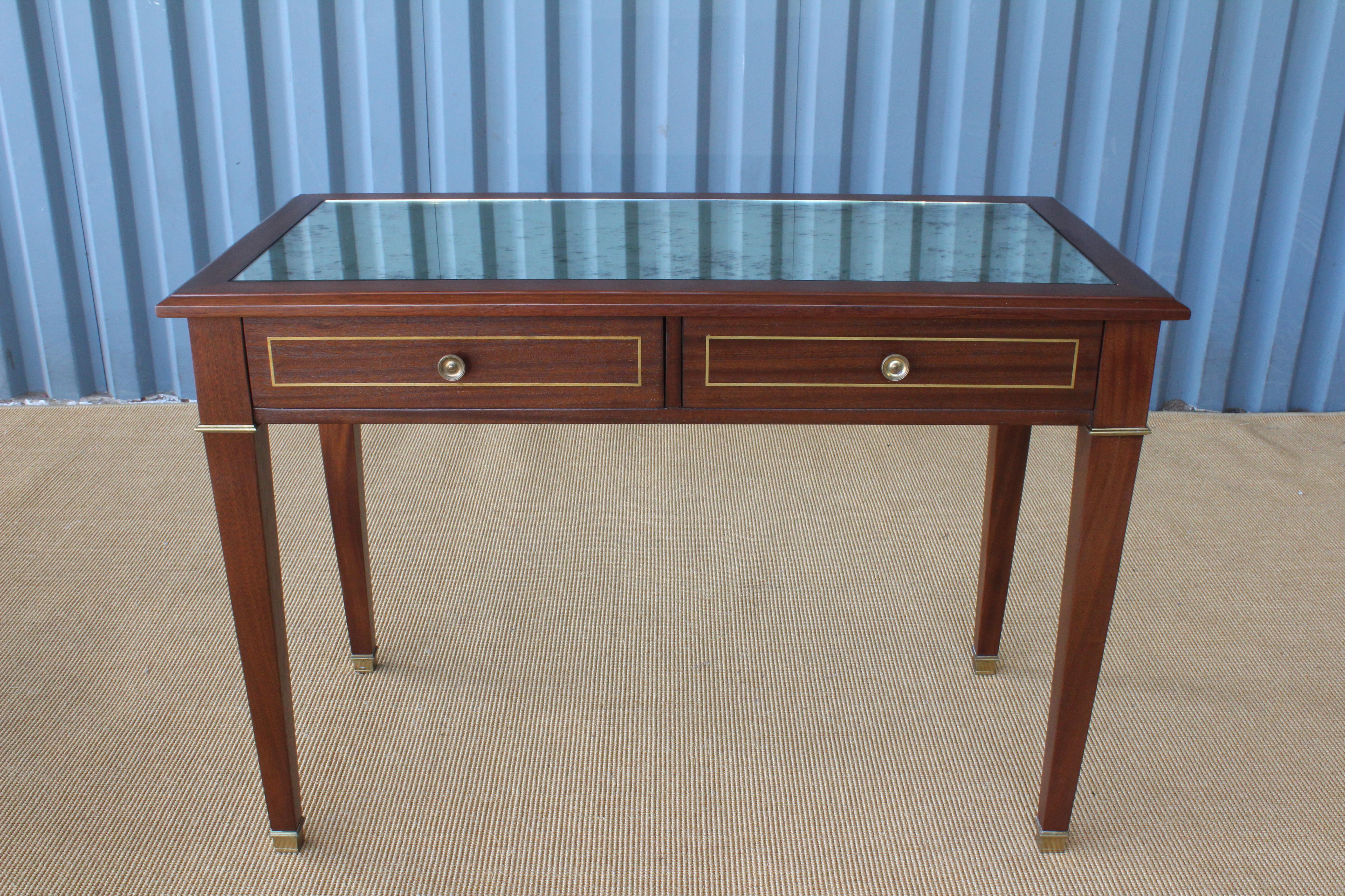 1950s mahogany jeweler's desk. Perfect use for a console table. Finished on all sides. Features brass accents, two drawers, and an antique mirror top. 
Recently refinished.