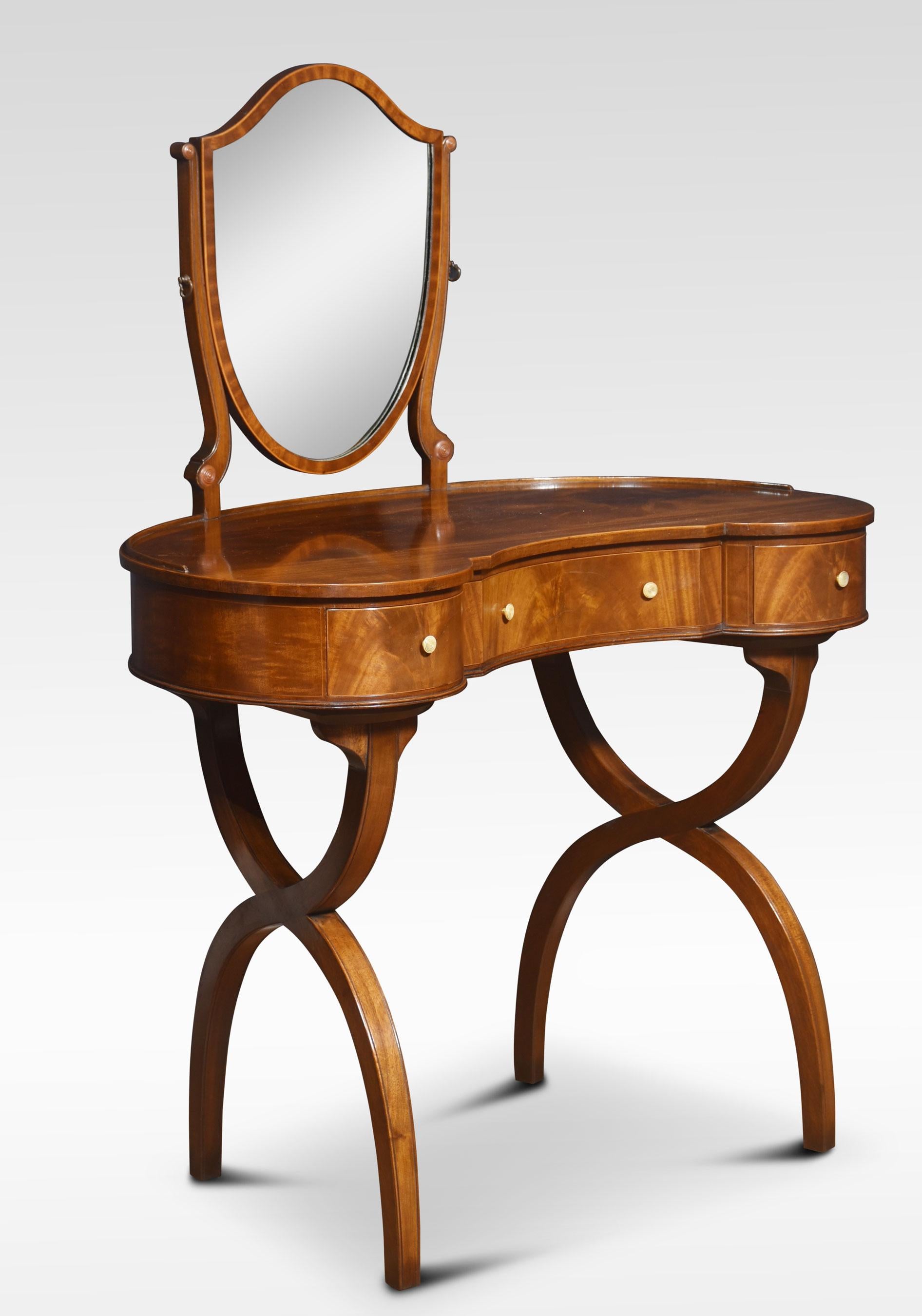 Mahogany kidney-shaped lady’s dressing table, the shield-shaped adjustable mirror supported on slender mahogany supports, to the well-figured kidney-shaped top. The frieze is fitted with three drawers with brass handles. All raised up on x-shaped